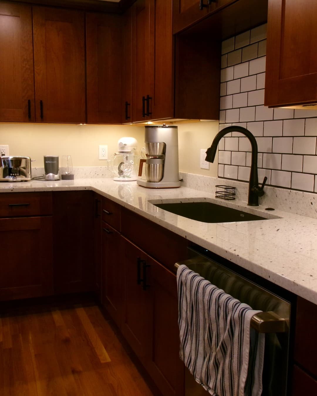 Kitchen sink area in a Fayetteville, NY remodel with granite countertops, wood cabinetry, and tiled backsplash.