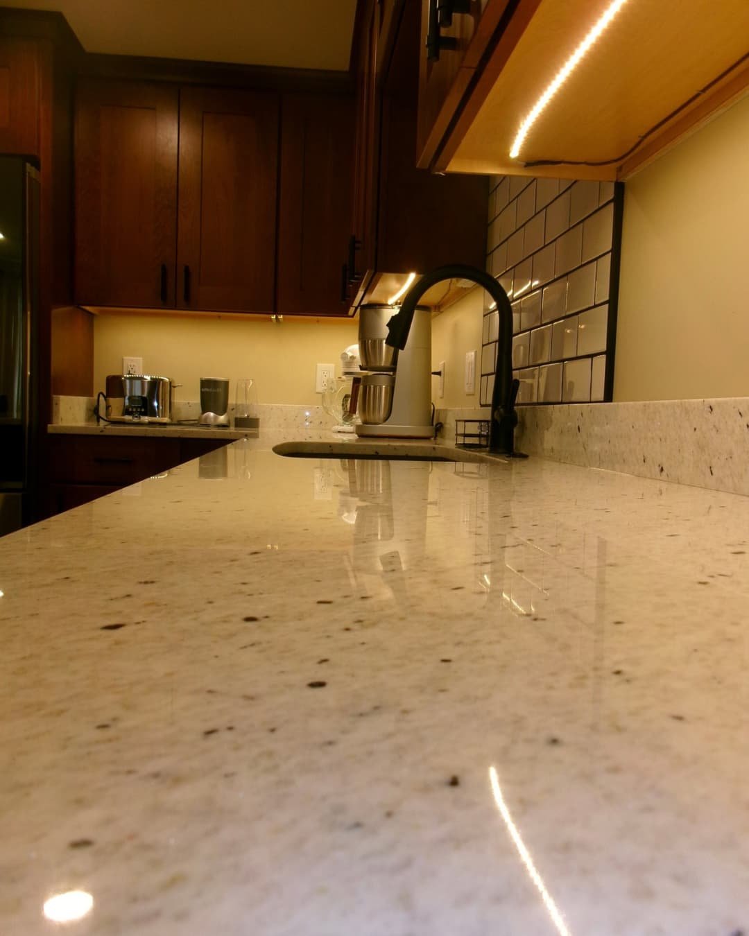 Granite countertop detail in a Central New York kitchen renovation with wood cabinetry and tiled wall finish.