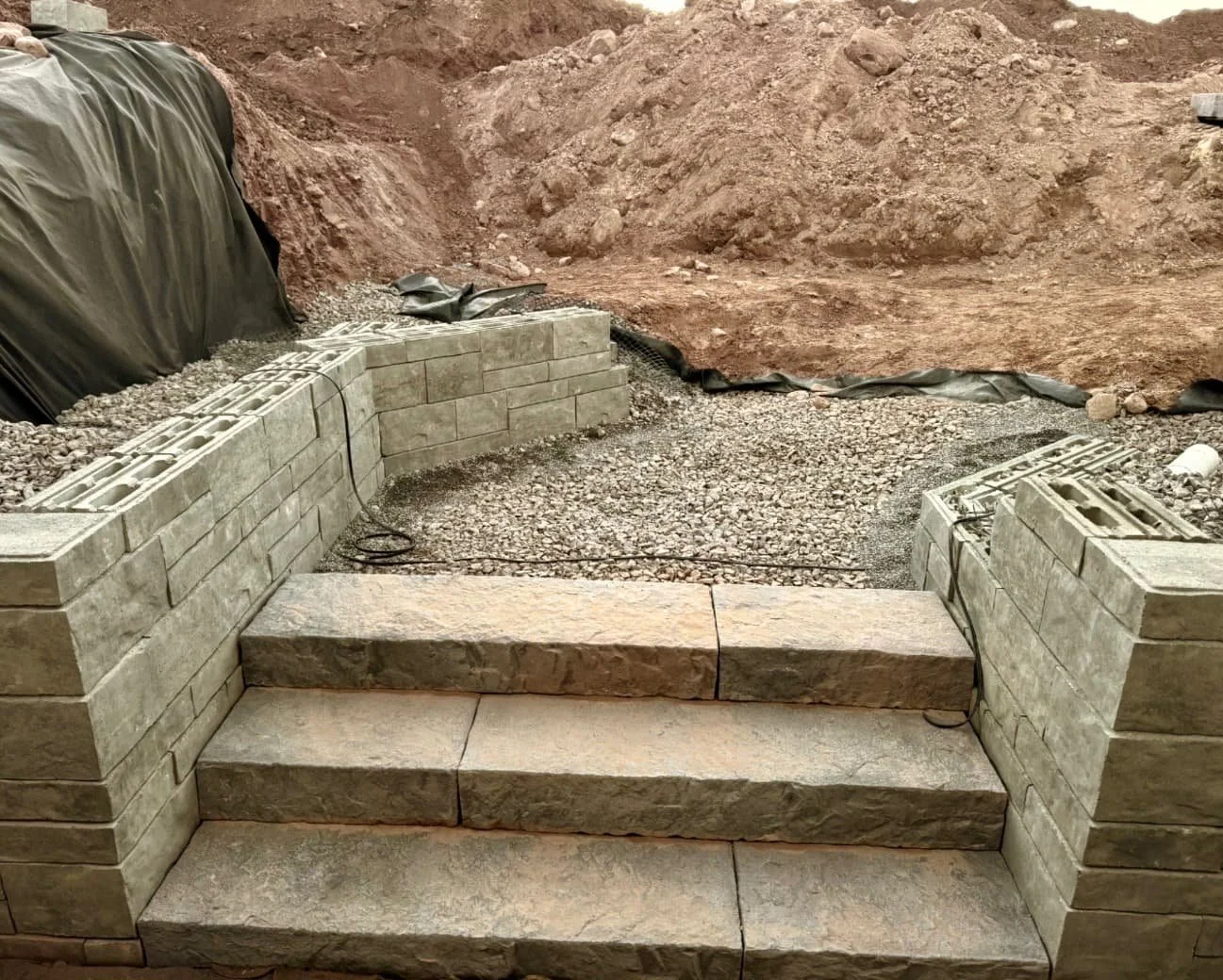 Retaining wall construction detail at a Skaneateles, NY property showing stone placement and active hardscape installation.