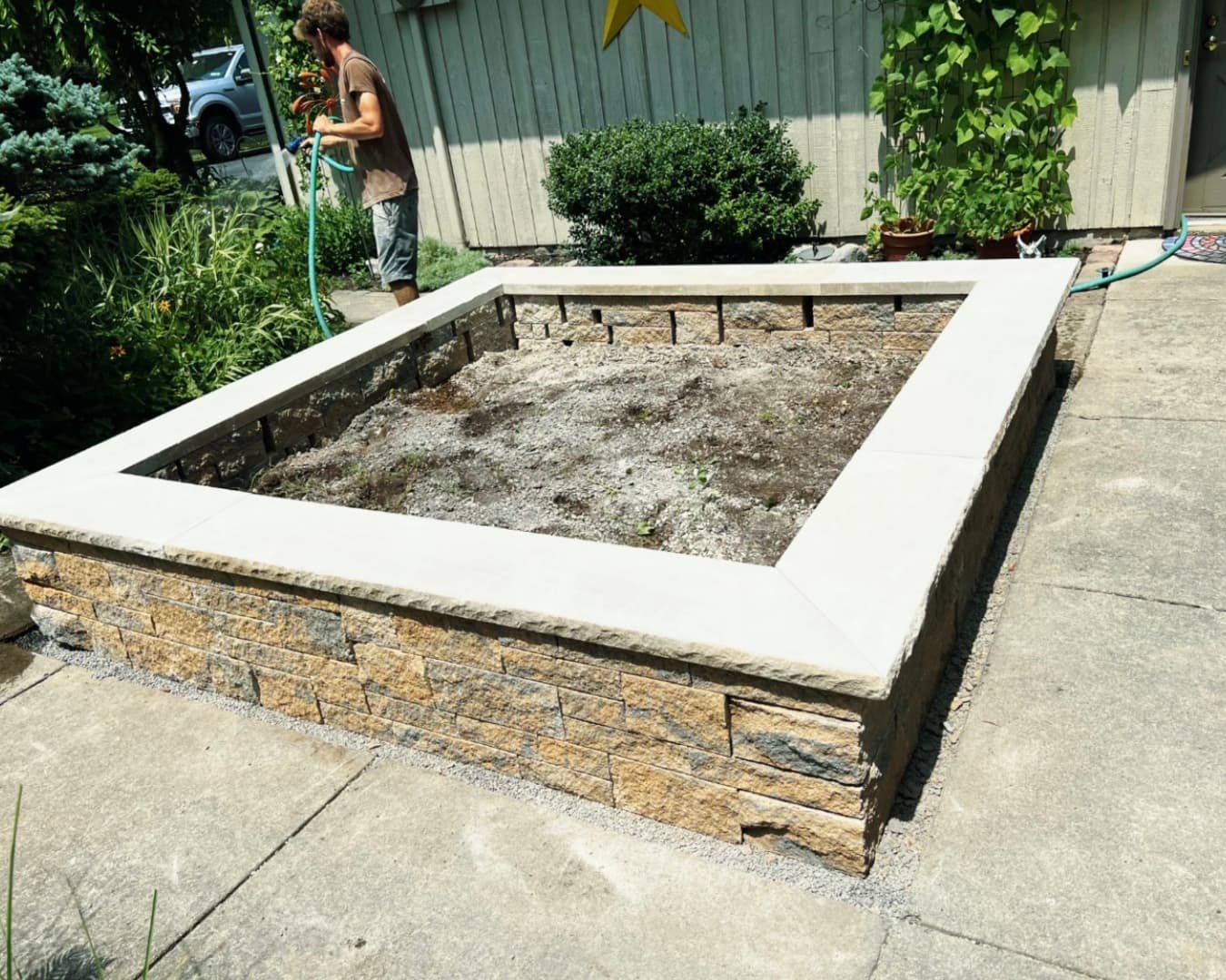 Custom outdoor planter box at a Skaneateles, NY home with stone veneer sides and a clean square design.