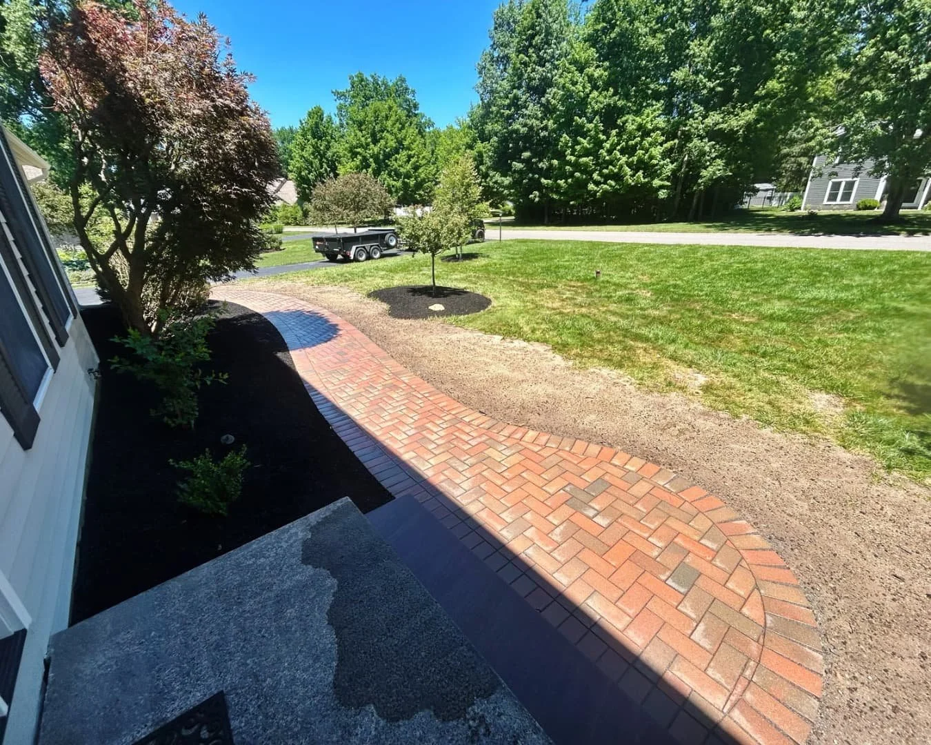 Curved entry walkway by the driveway completed by Pines and Pavers in Manlius, New York.