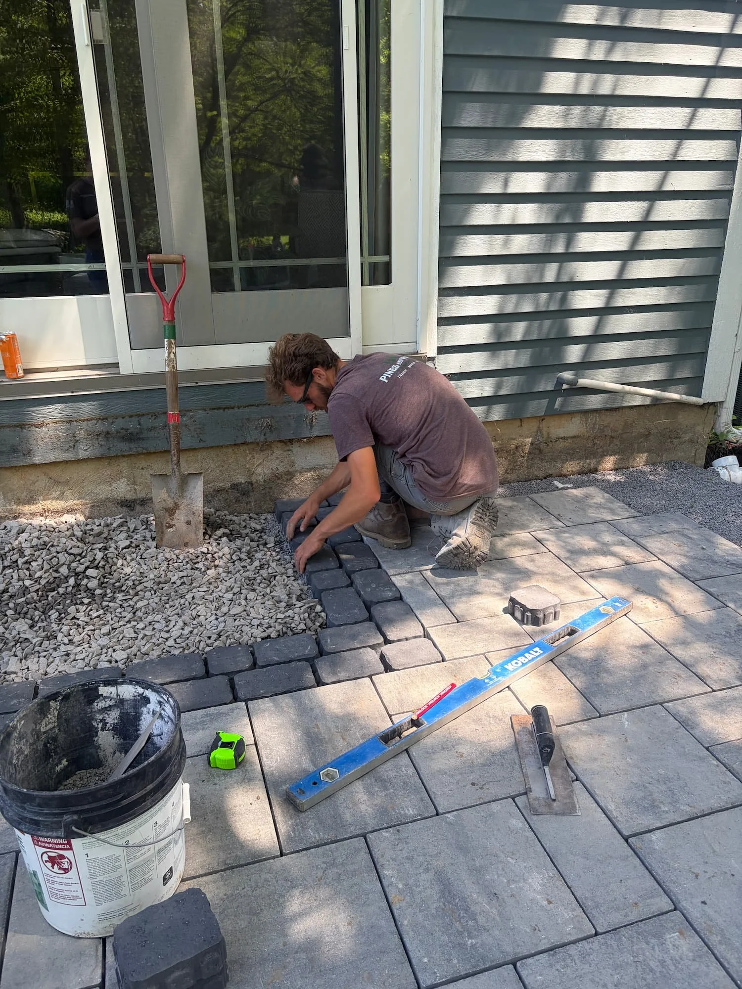 Hardscape installer cutting and fitting patio pavers for a custom outdoor living space in Central New York.