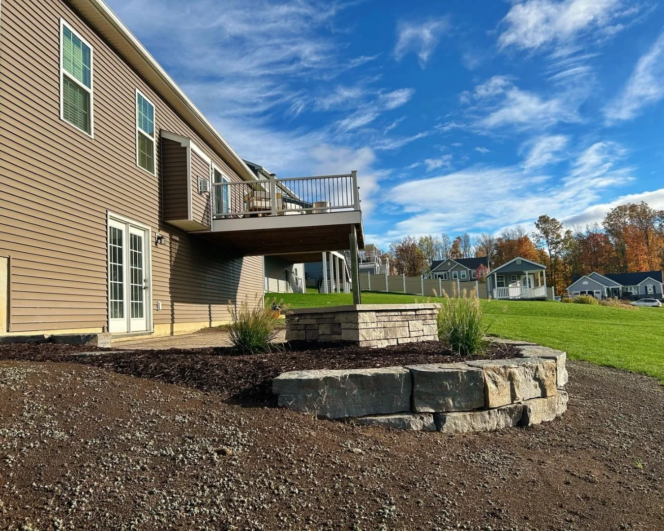 Large backyard patio and seating wall completed by Pines and Pavers in Lysander, New York.