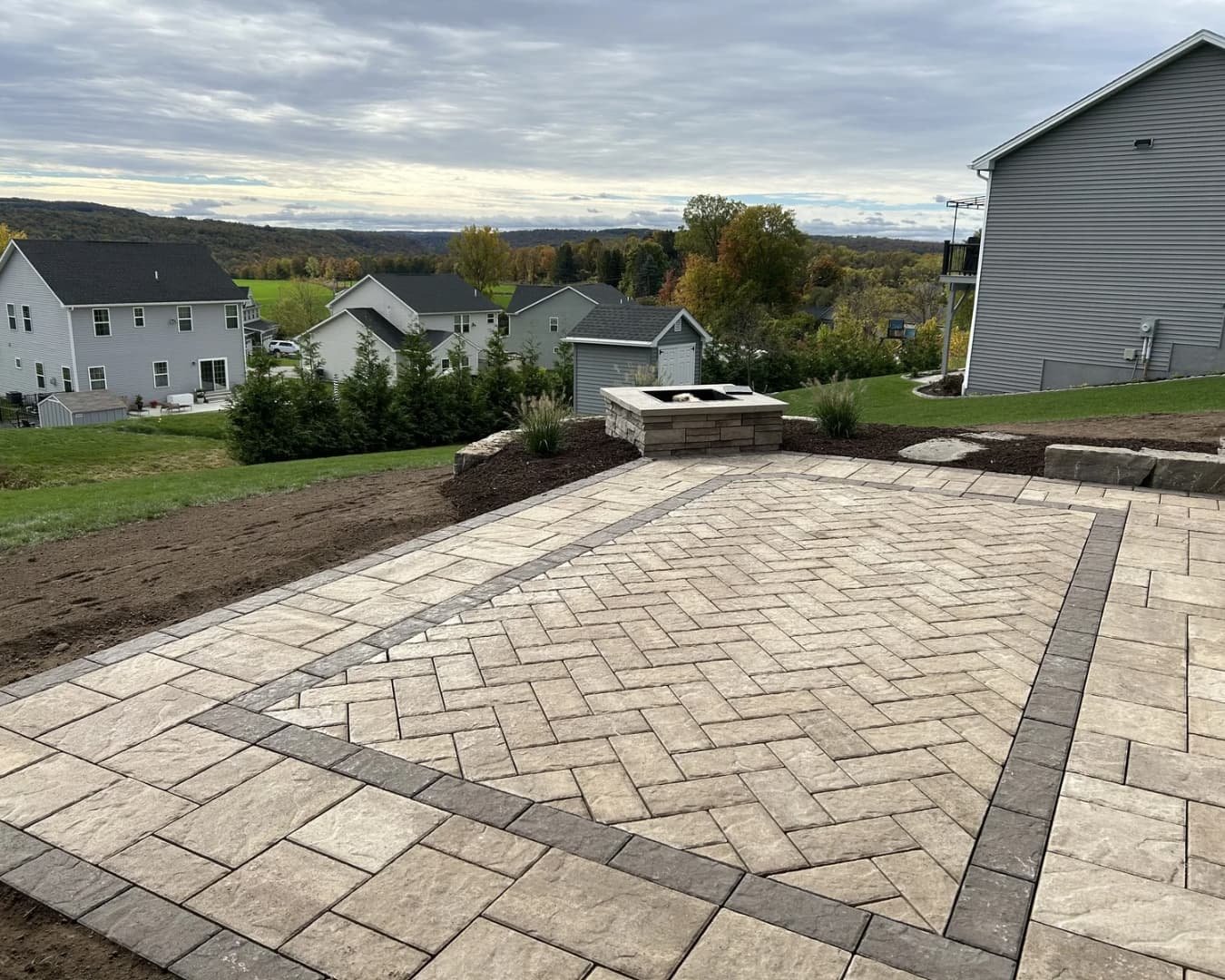 Wide backyard view of a residential hardscape project in progress in Upstate New York.