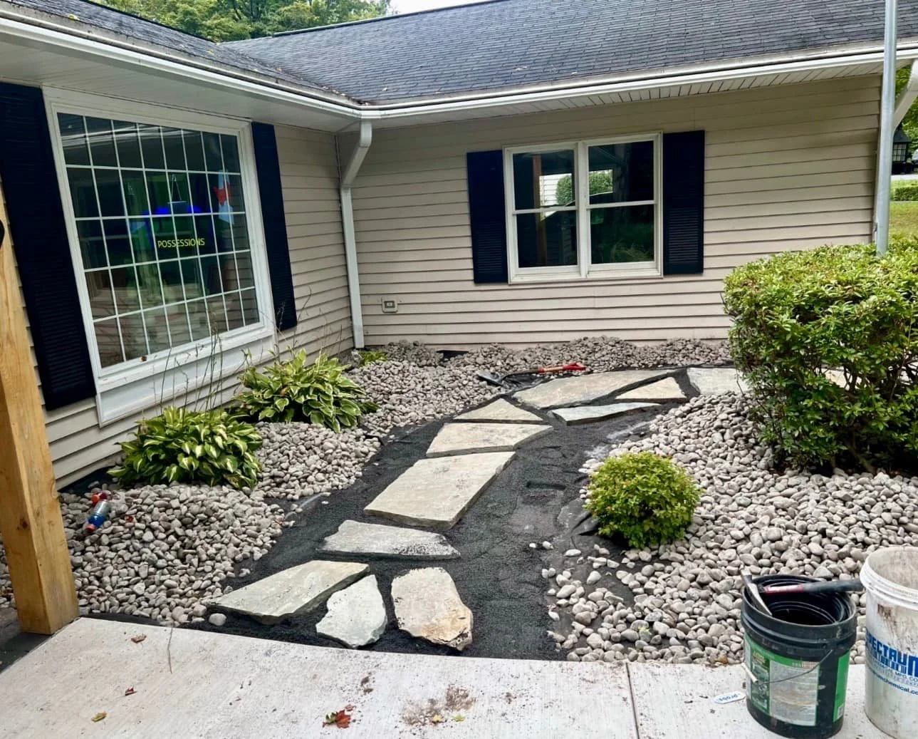 Front entry shrub and stone bed at a Cazenovia, NY home with decorative rock, fresh edging, and updated landscaping.