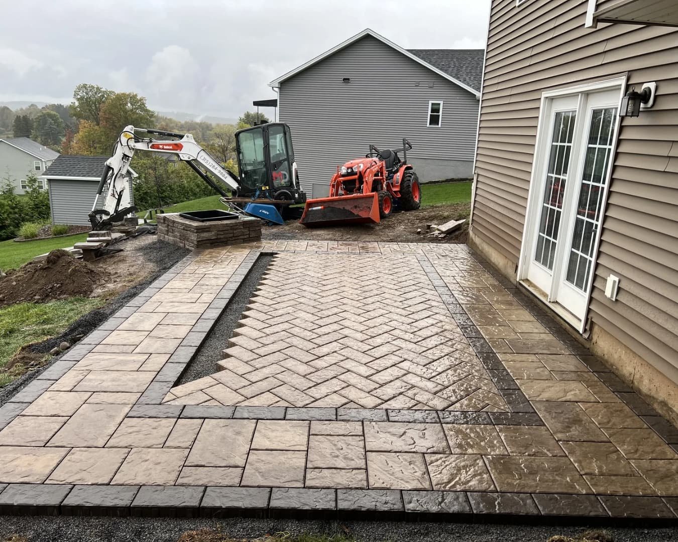 Side view of a home with new hardscape and grading work underway in Upstate New York.