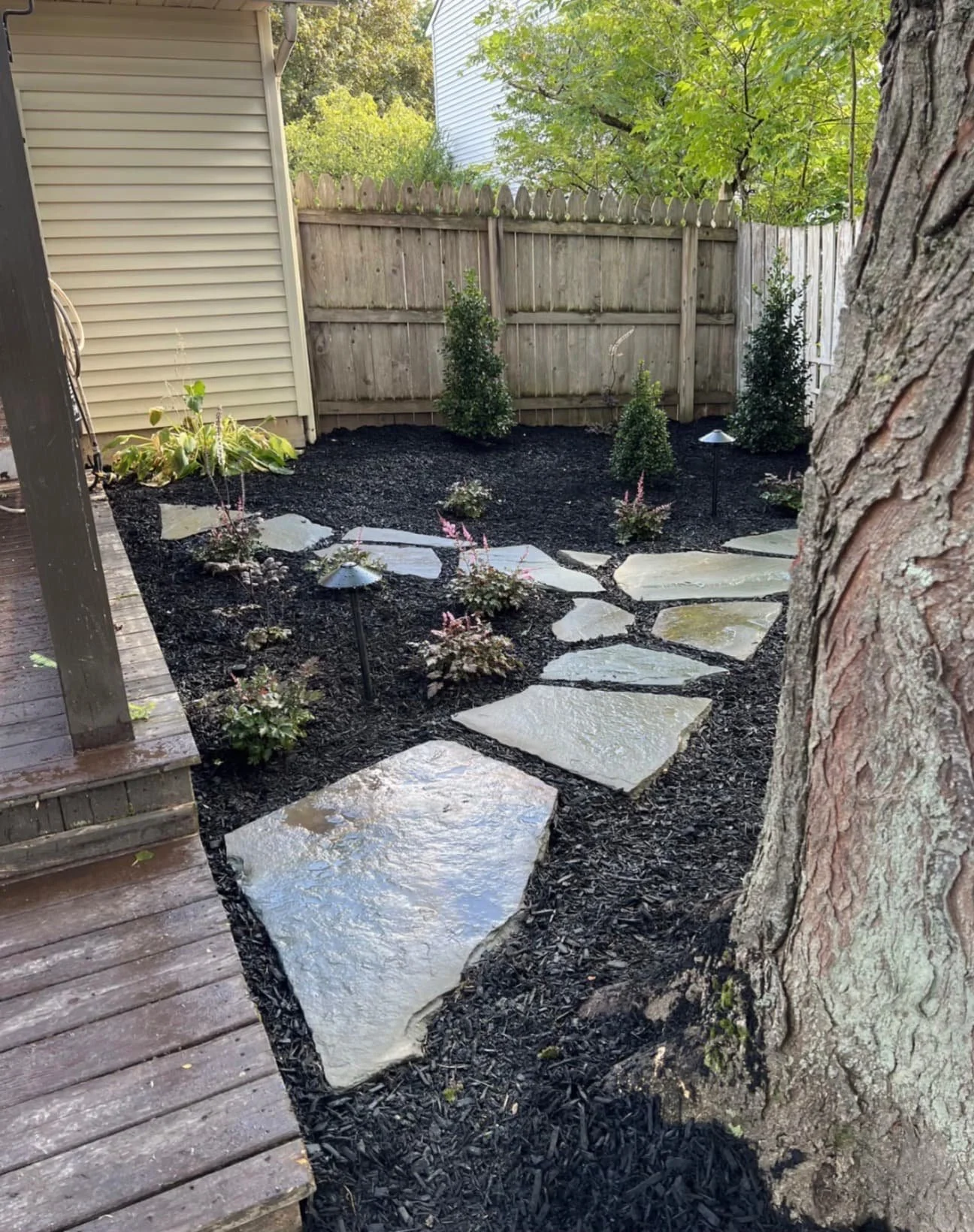 Backyard garden path at a Skaneateles, NY home with stepping stones, fresh mulch, and decorative planting beds.