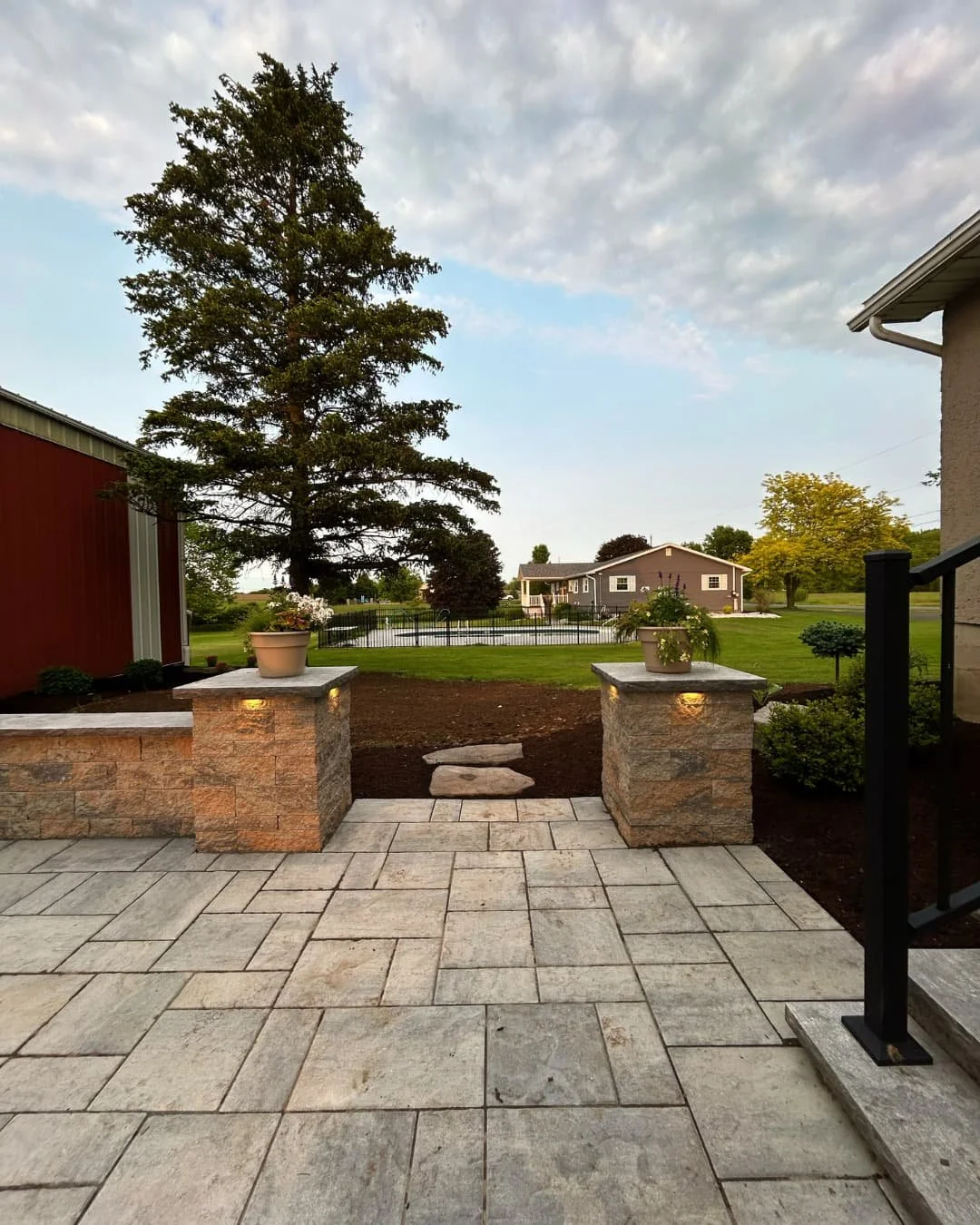 Paver patio entry with stone pillars completed by Pines and Pavers in Fayetteville, New York.