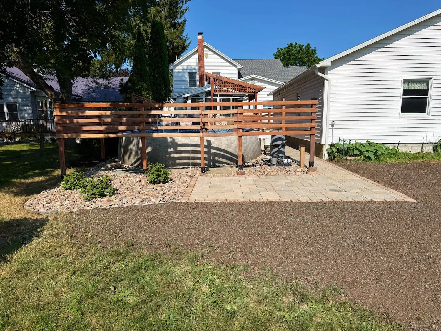 Completed paver patio installed alongside a raised wood deck in Central New York.