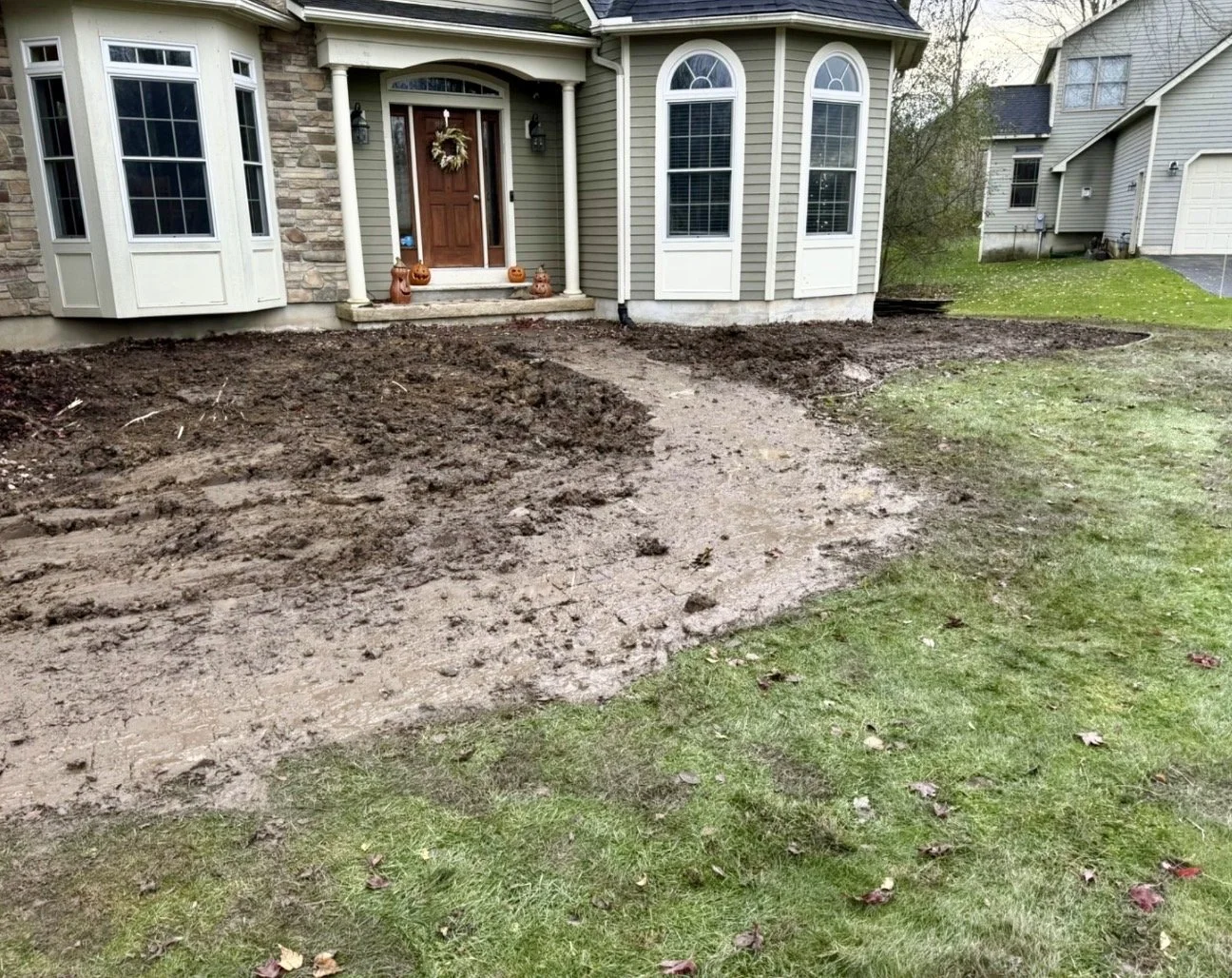 Curved front landscape bed preparation at a Cazenovia, NY home with fresh soil shaping and lawn transition.