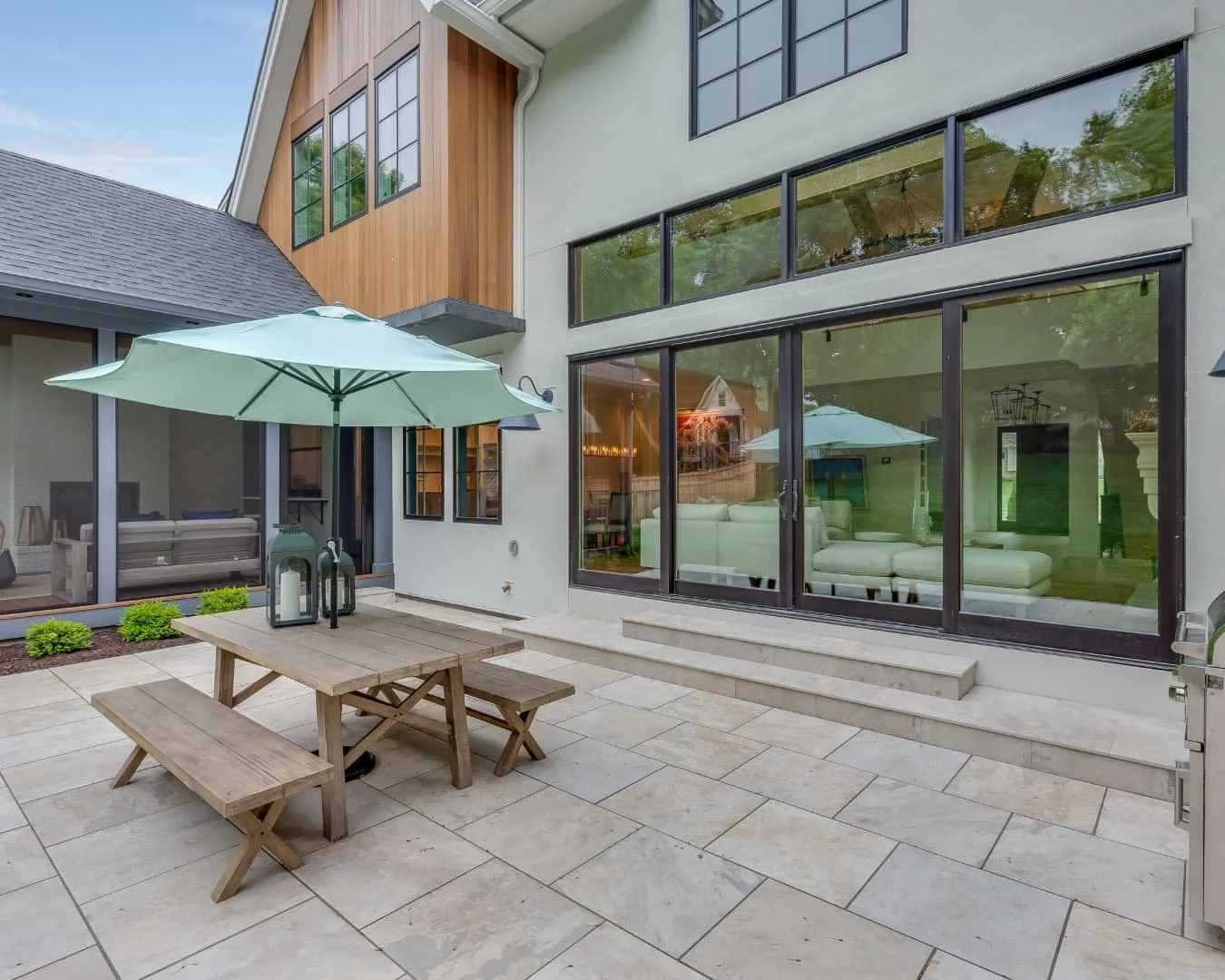 Modern patio inspiration with a clean paver terrace, lounge seating, and large windows overlooking the yard.