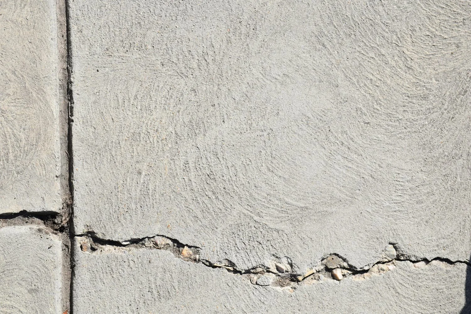 Cracked concrete surface showing winter damage and the need for proper hardscape planning and repair in Central NY.