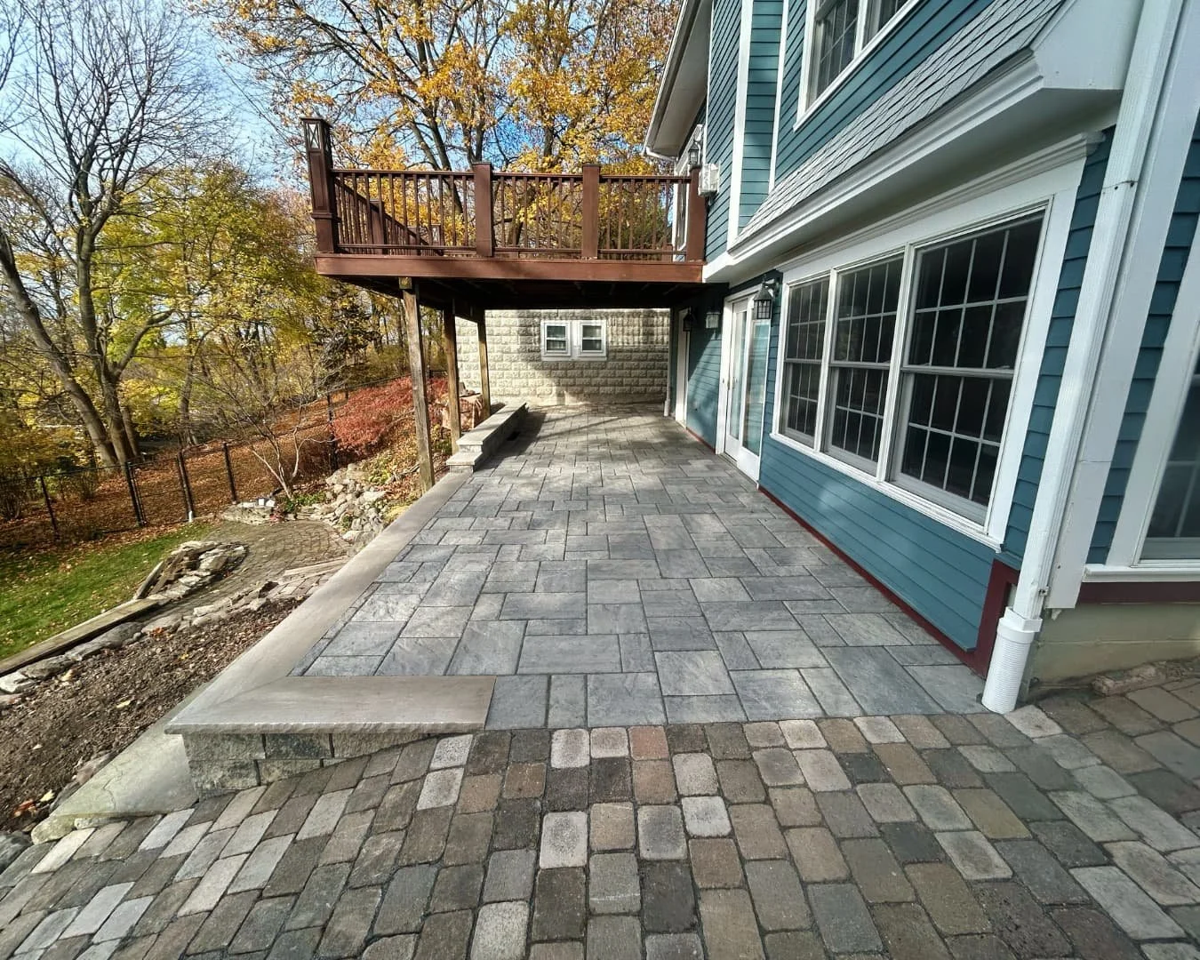 Raised patio with stone step detail completed by Pines and Pavers at a Central New York residence.