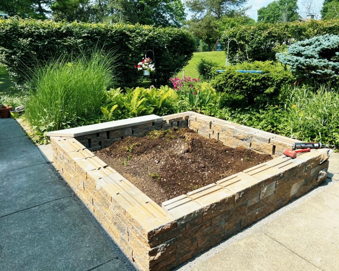 Raised bed construction at a Central New York home with stone-faced walls and fresh soil ready for planting.