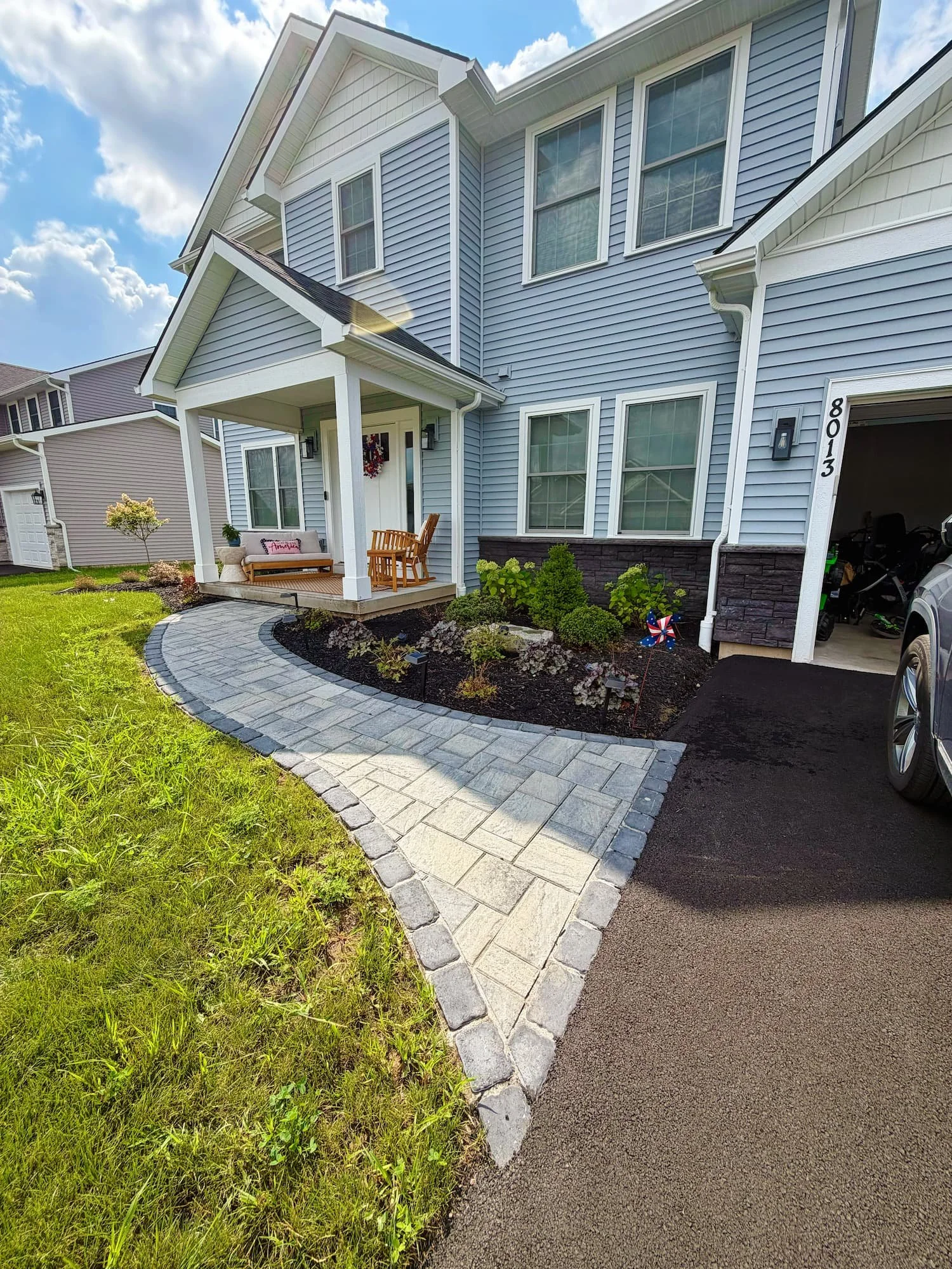 Finished front yard landscape design with a paver walkway and planted garden beds in Central NY.