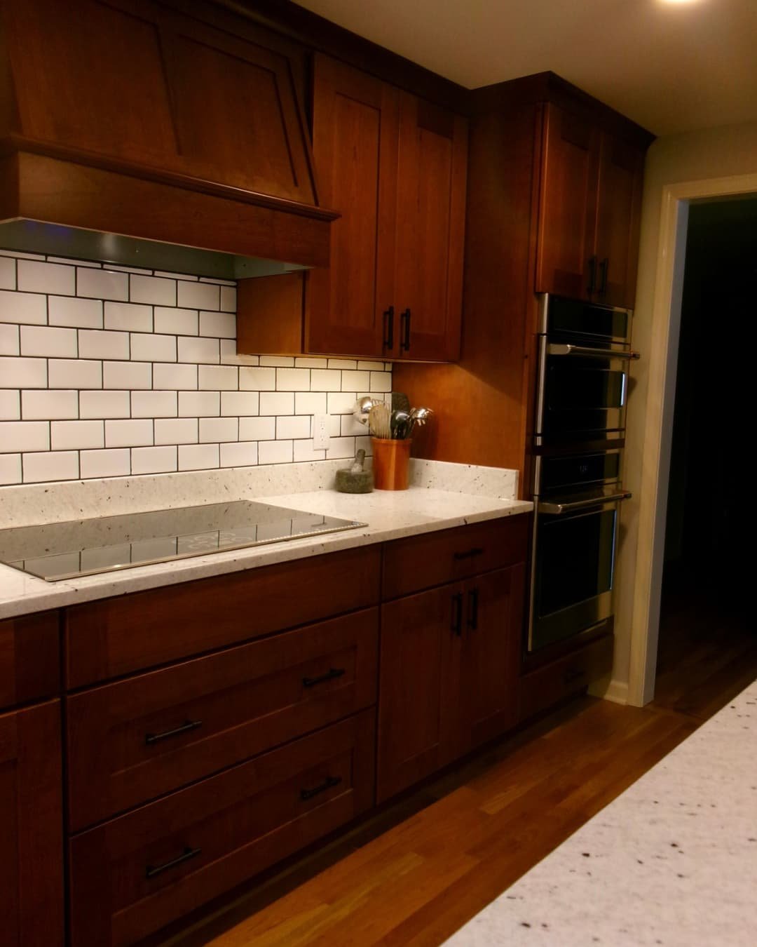 Granite countertop and tiled backsplash in an Upstate New York kitchen renovation with rich wood cabinets.