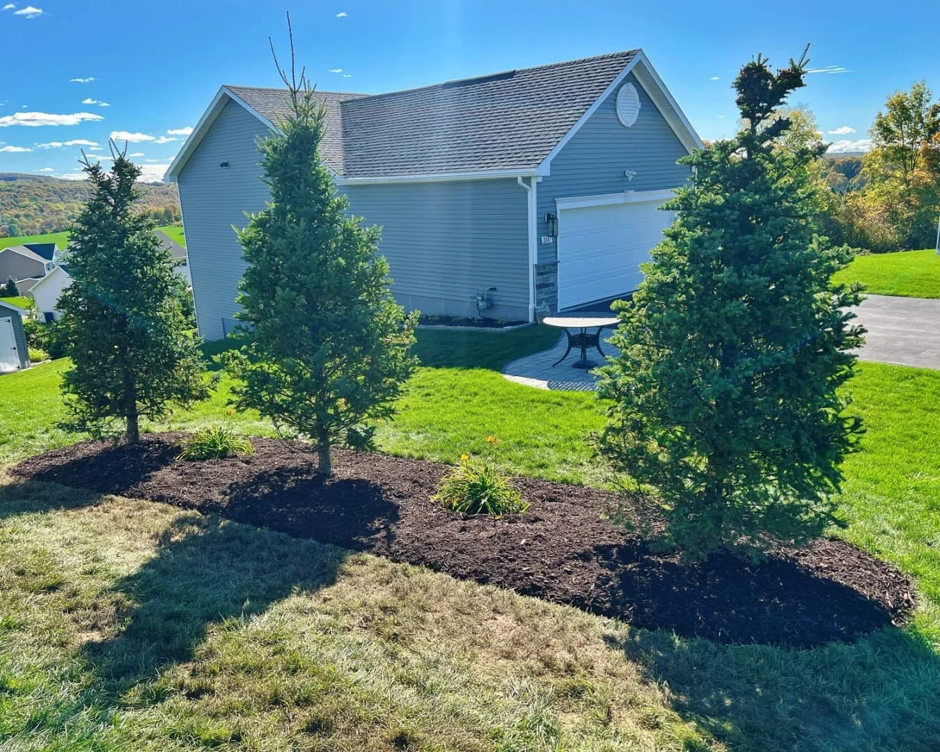 Ornamental tree island bed wide view completed by Pines and Pavers in Lysander, New York.