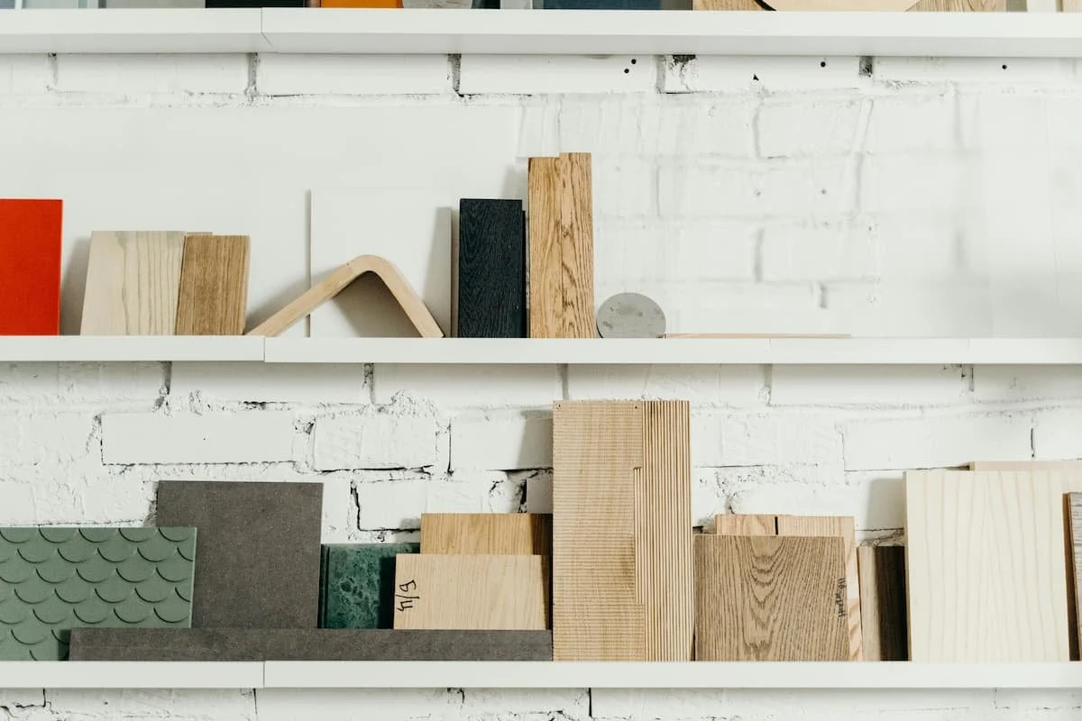 Shelving display featuring wood, tile, and construction material samples arranged inside a modern design studio.