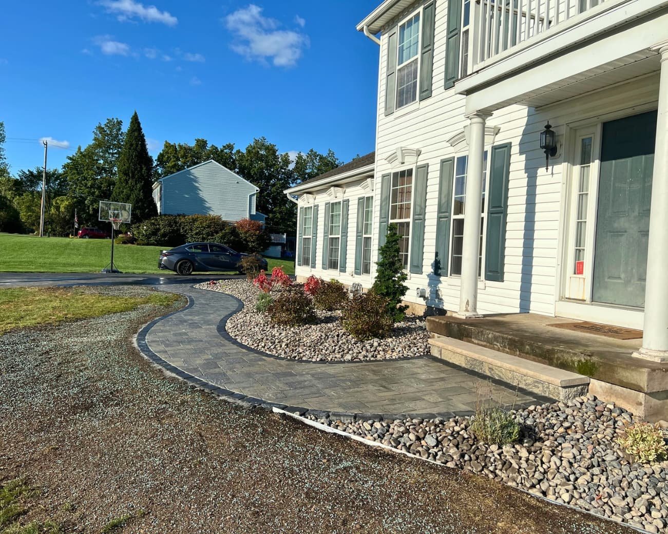 Curved front entry patio and paver landing at a Skaneateles, NY residence with decorative stone detailing.