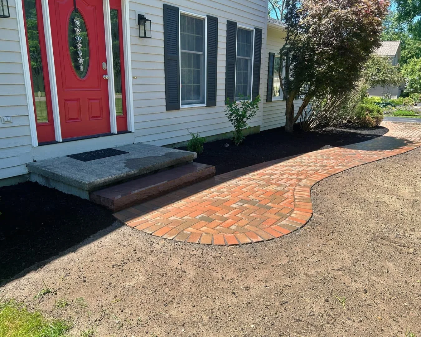 Front yard landscape and entry view completed by Pines and Pavers in Manlius, New York.