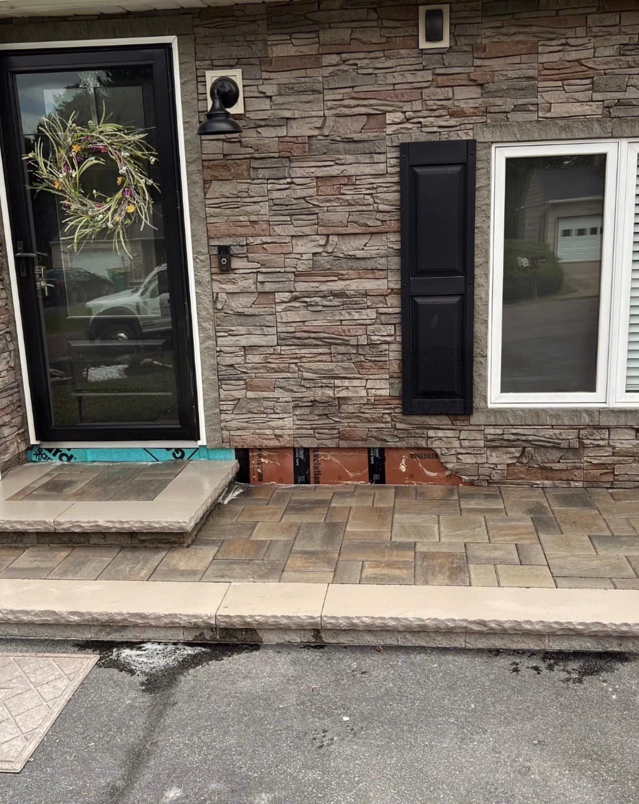 Front door paver landing at a Syracuse-area home with stone facade detailing and a clean, updated entry design.