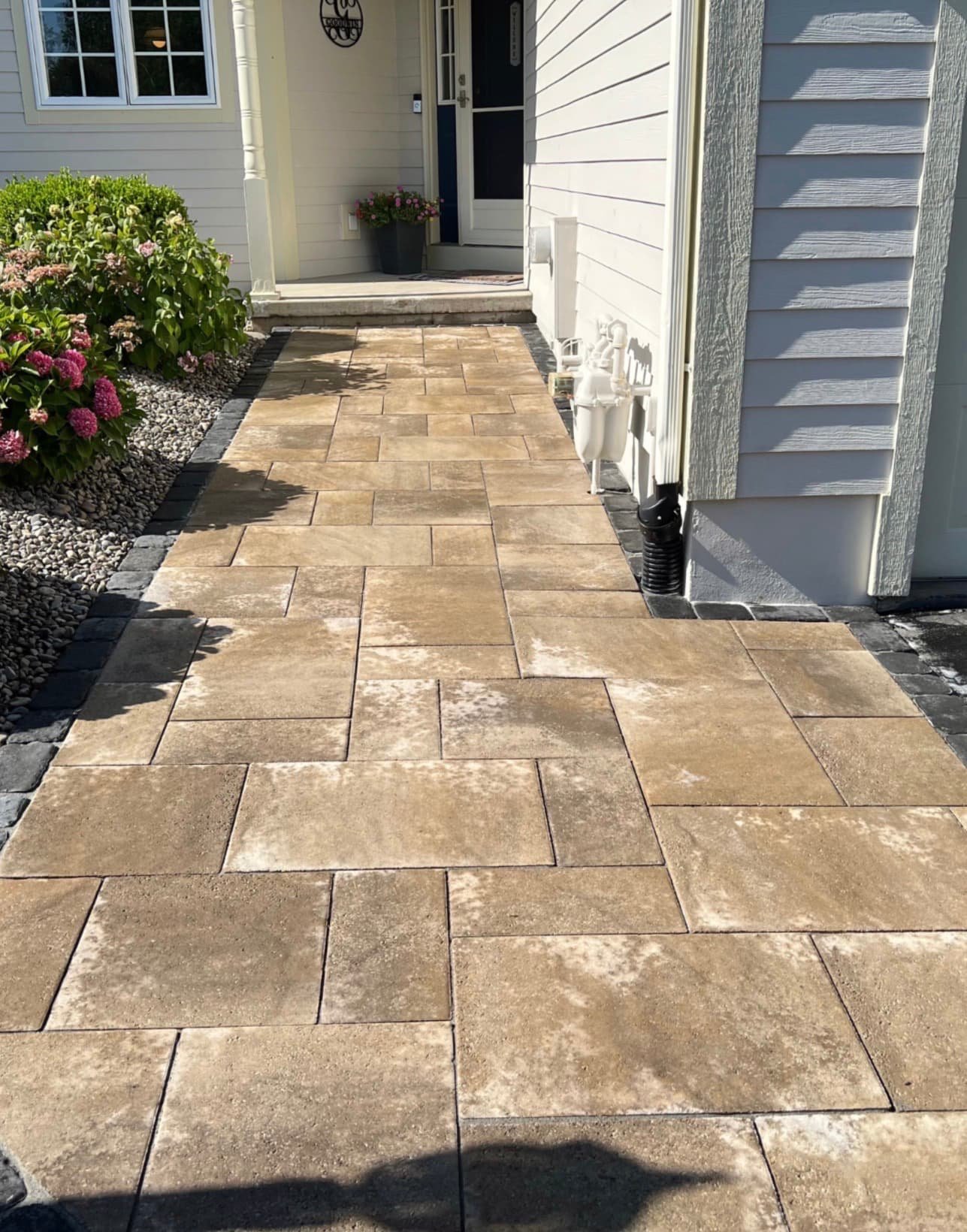Tan paver front walkway at an Upstate New York home with a clean layout leading to the entry.