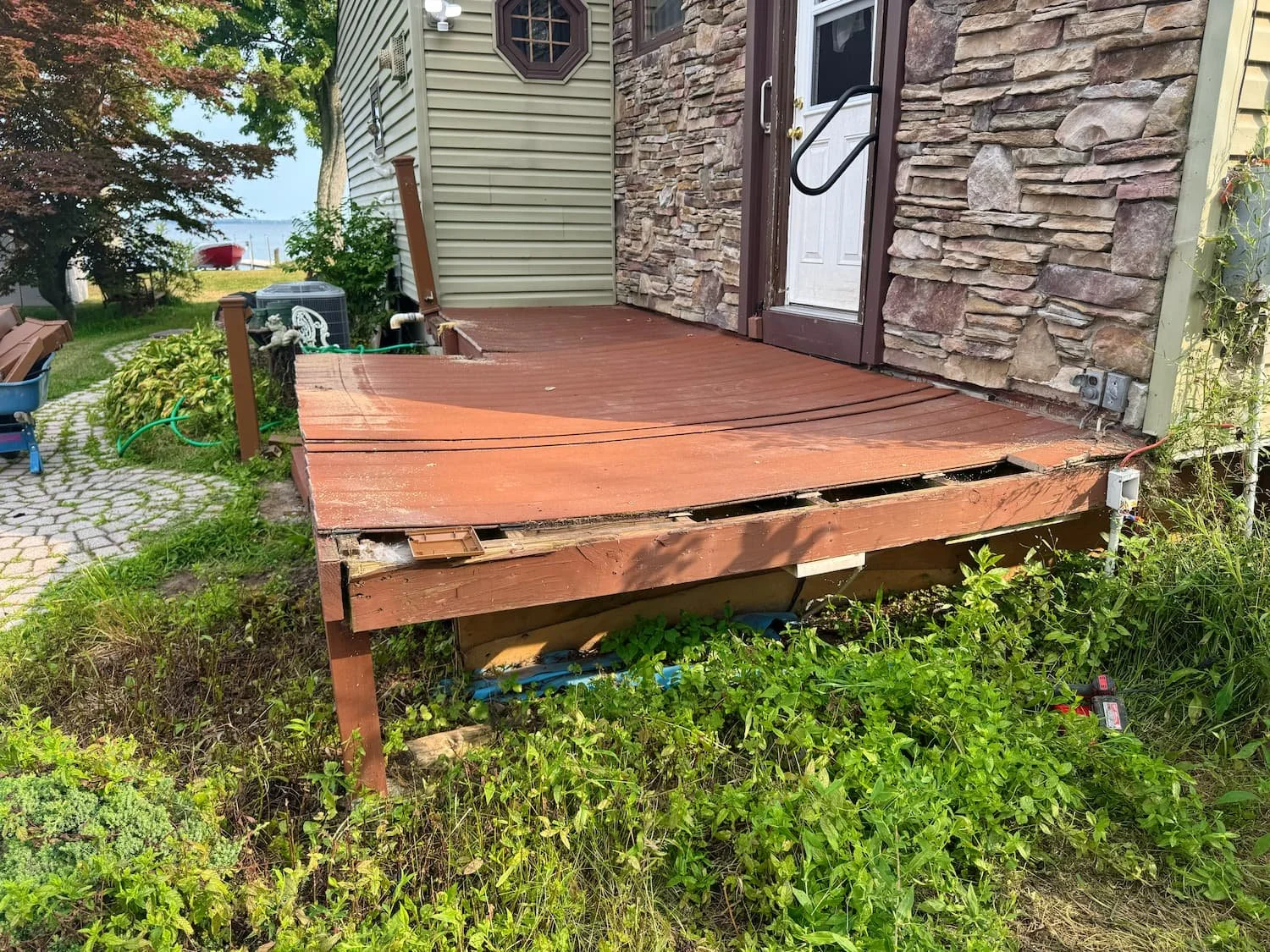 Old backyard deck before renovation showing worn decking, damaged edges, and missing railing in Central NY