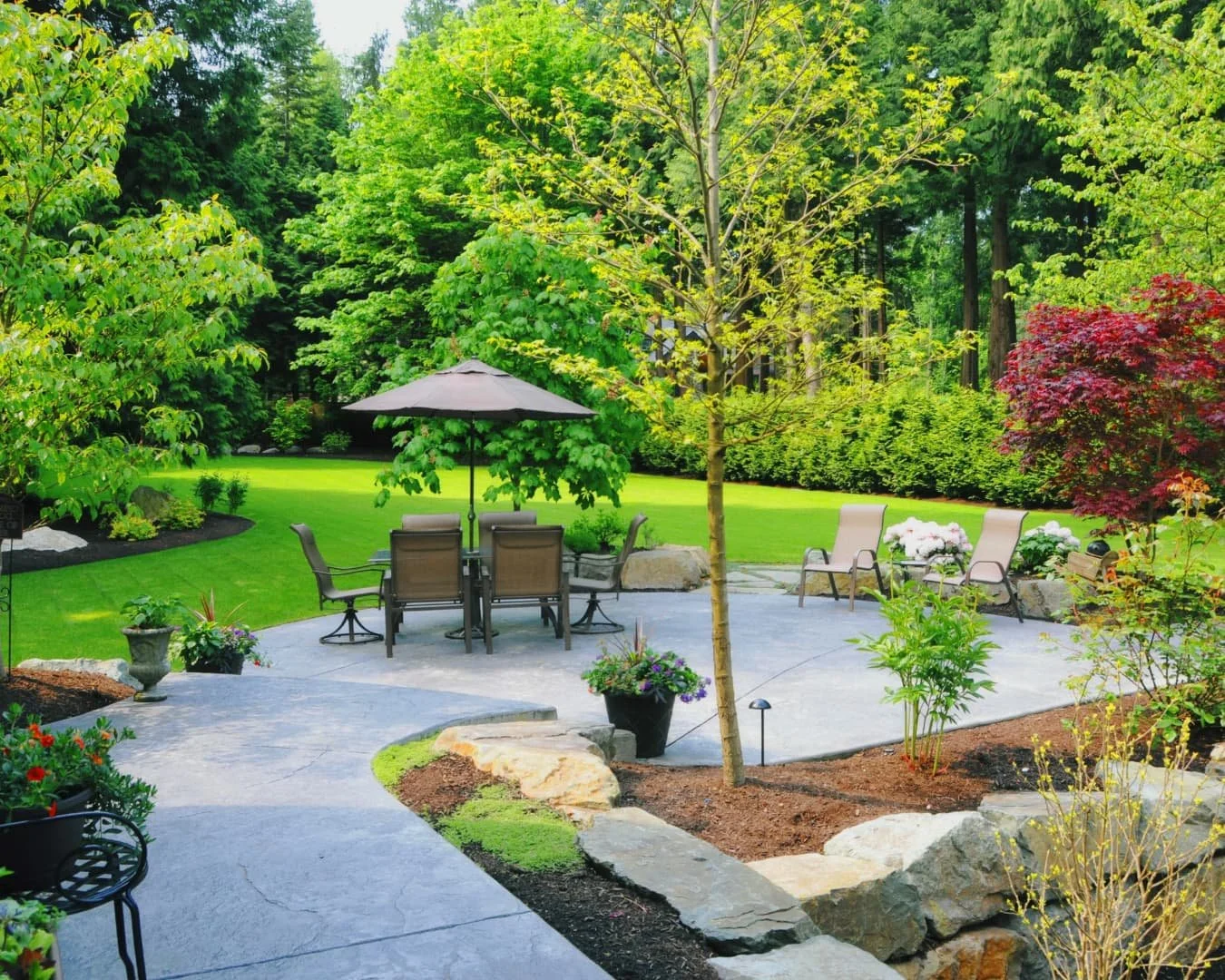Patio inspiration featuring a curved paver walkway and backyard seating area surrounded by landscaping.