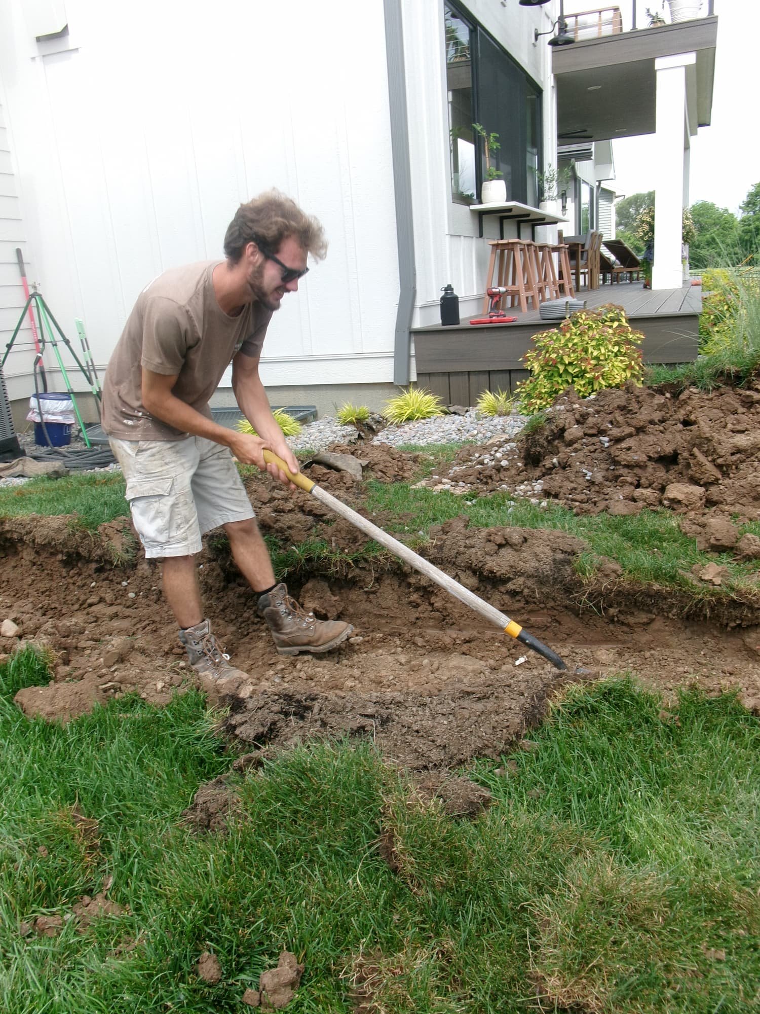 Backyard before landscape renovation showing an unfinished garden bed and patchy lawn in Central NY