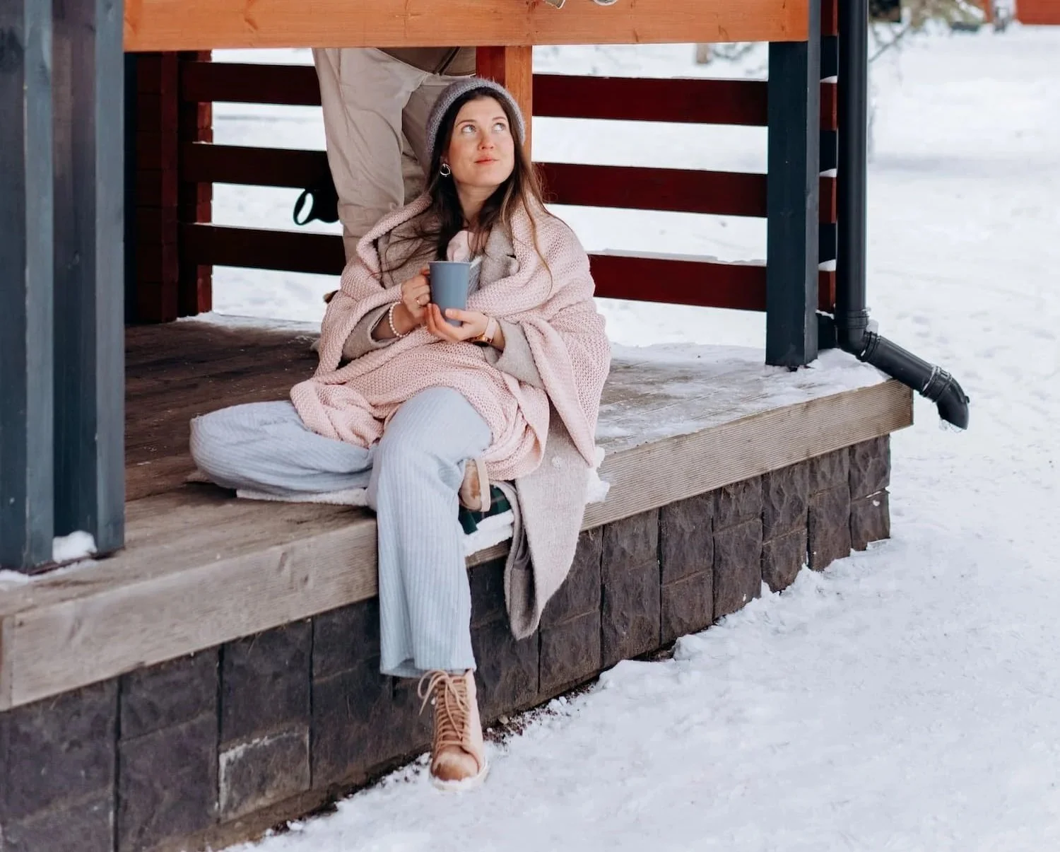Modern covered patio with black slatted walls and built-in bench seating overlooking a snowy landscape, creating a cozy outdoor retreat for enjoying every season.