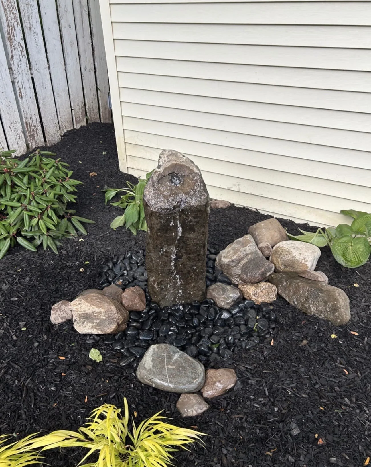 Rock bed foundation landscaping at an Upstate New York home with decorative stone, fresh mulch, and low-maintenance plantings.
