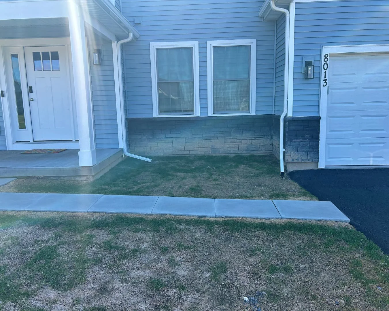     Front door and porch area before concrete walkway installation at a residential home.
