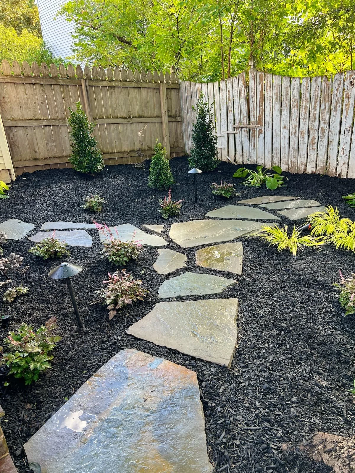 Natural stone garden pathway surrounded by fresh mulch and landscaping in a Central New York backyard.