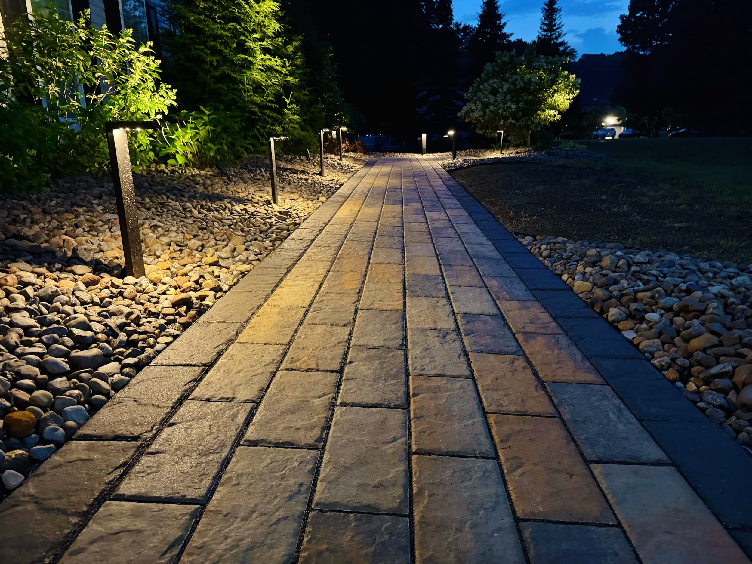 Custom paver walkway with integrated outdoor lighting and decorative stone landscaping in Central NY.