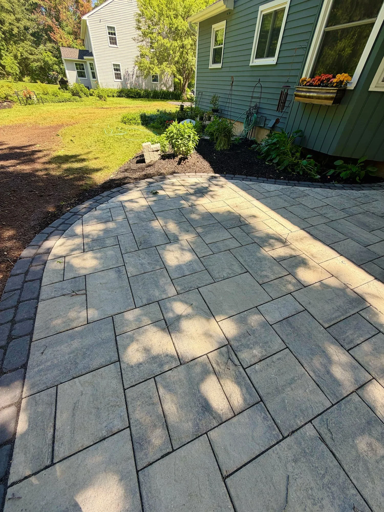 Custom paver patio and stone entry steps professionally integrated with a Central New York home.