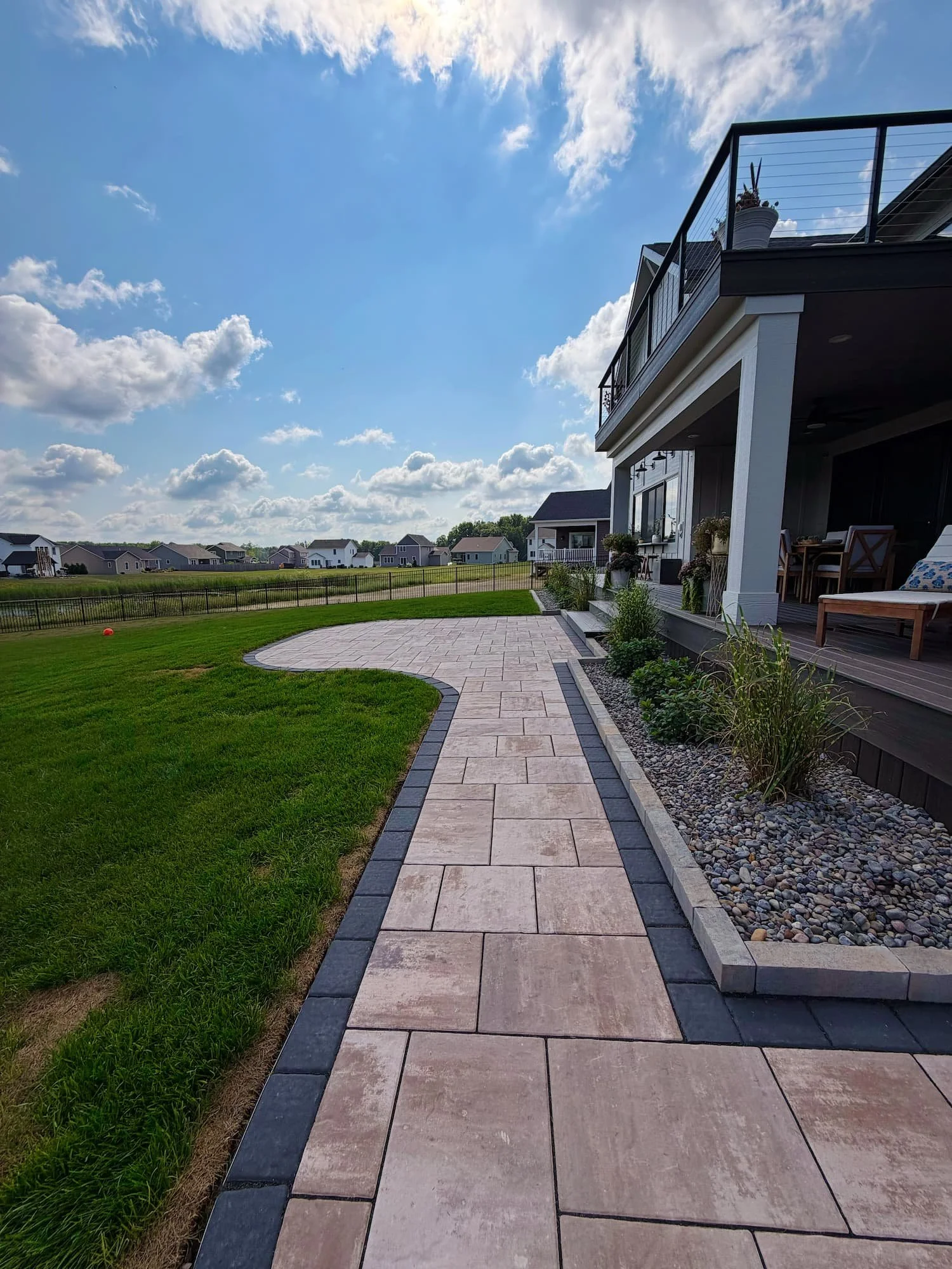 Curved paver patio installation with surrounding lawn at a Central New York home