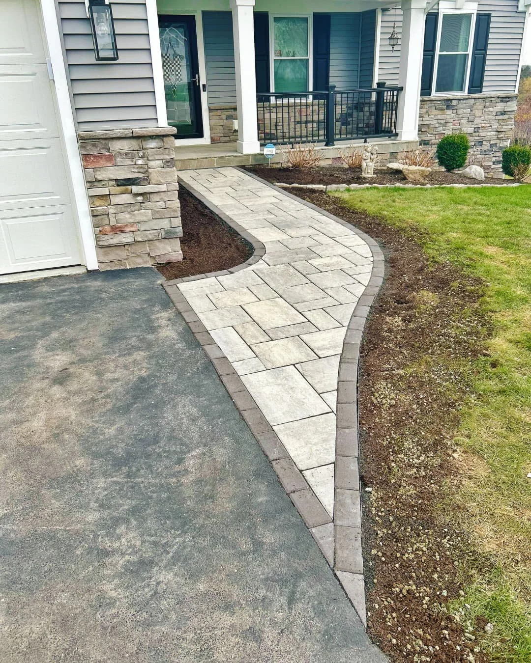     Curved front sidewalk beside the driveway with fresh landscape beds and clean edging.