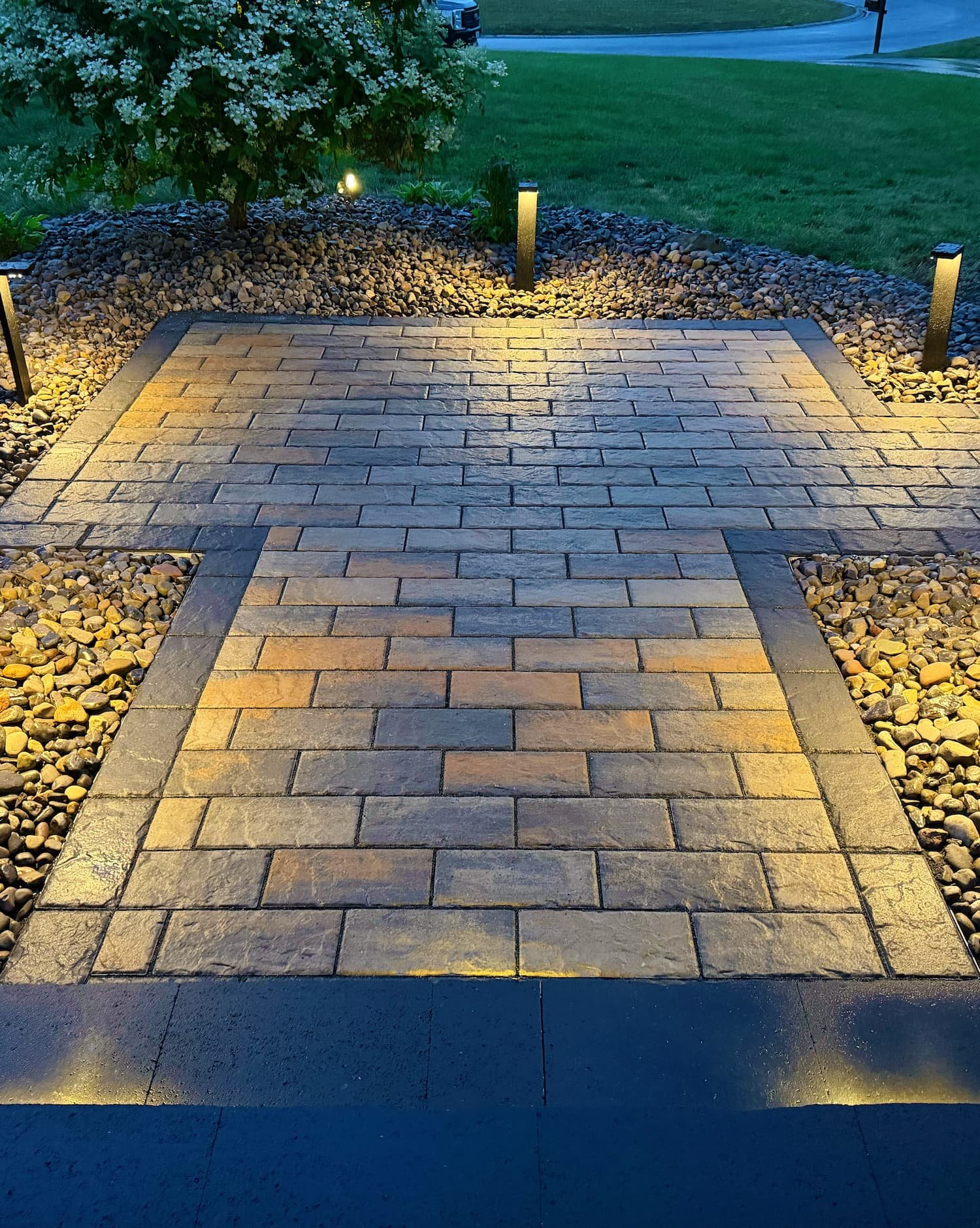 River rock landscape bed with shrubs alongside a Central NY home by Pines and Pavers.