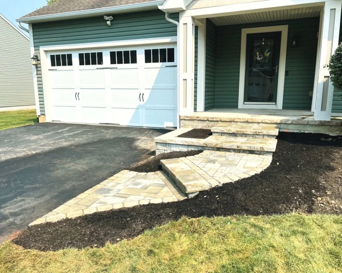 Curved paver steps and entry walkway at a Cazenovia, NY garage entrance with a custom hardscape design.