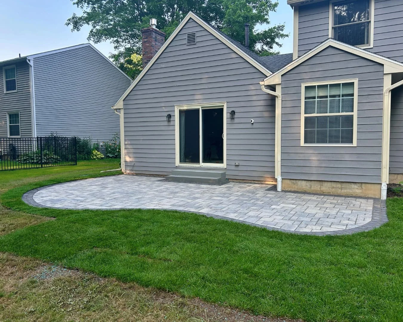 Rear patio with curved edge completed by Pines and Pavers in Baldwinsville, New York.