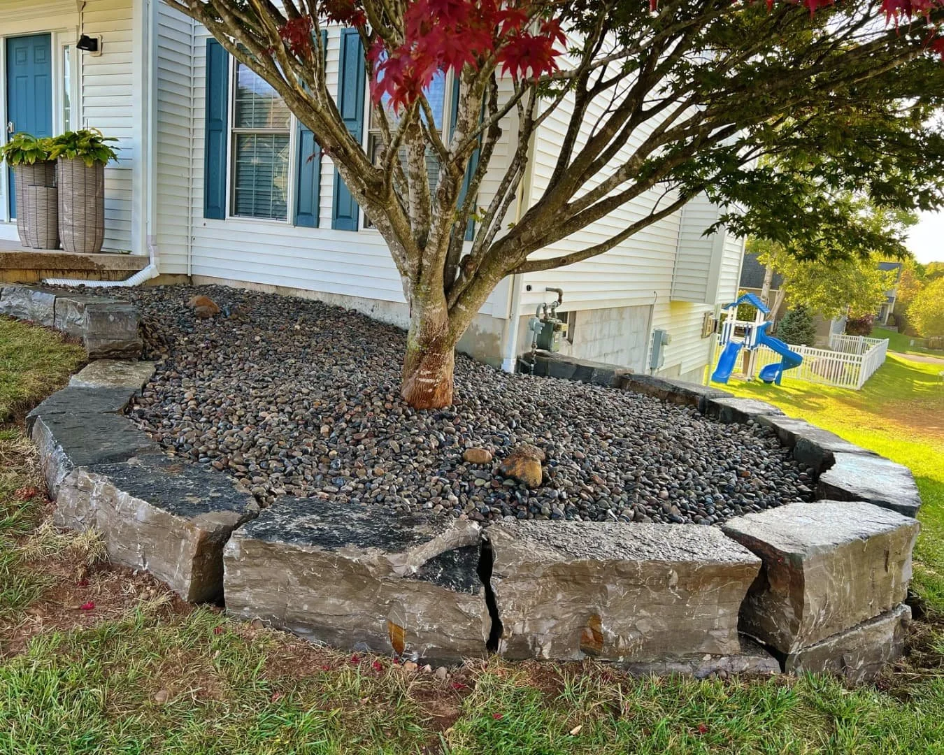 Side yard curved rock bed completed by Pines and Pavers in Lysander, New York.
