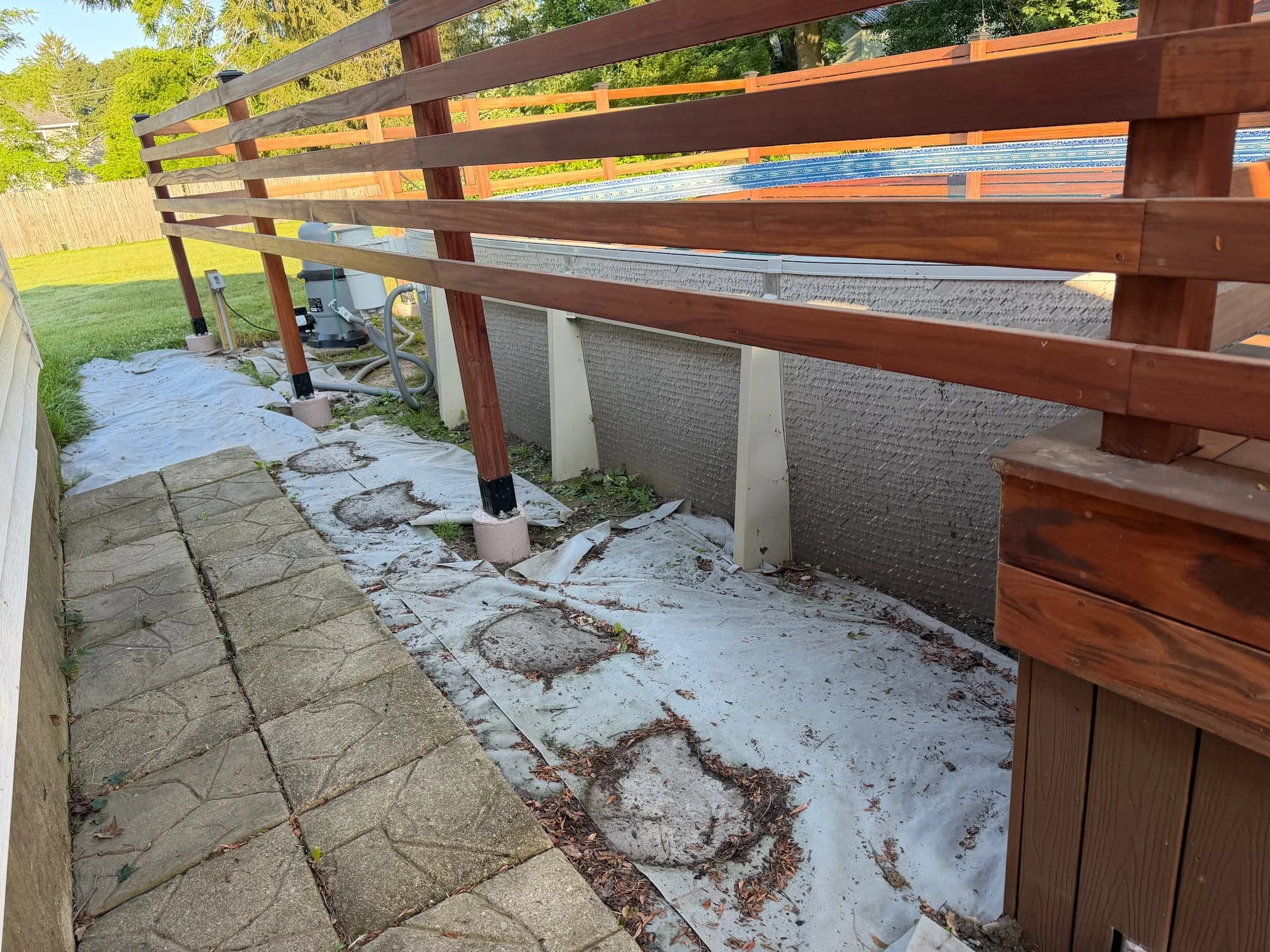 Paver patio taking shape beside a raised deck during a Central New York hardscape project.