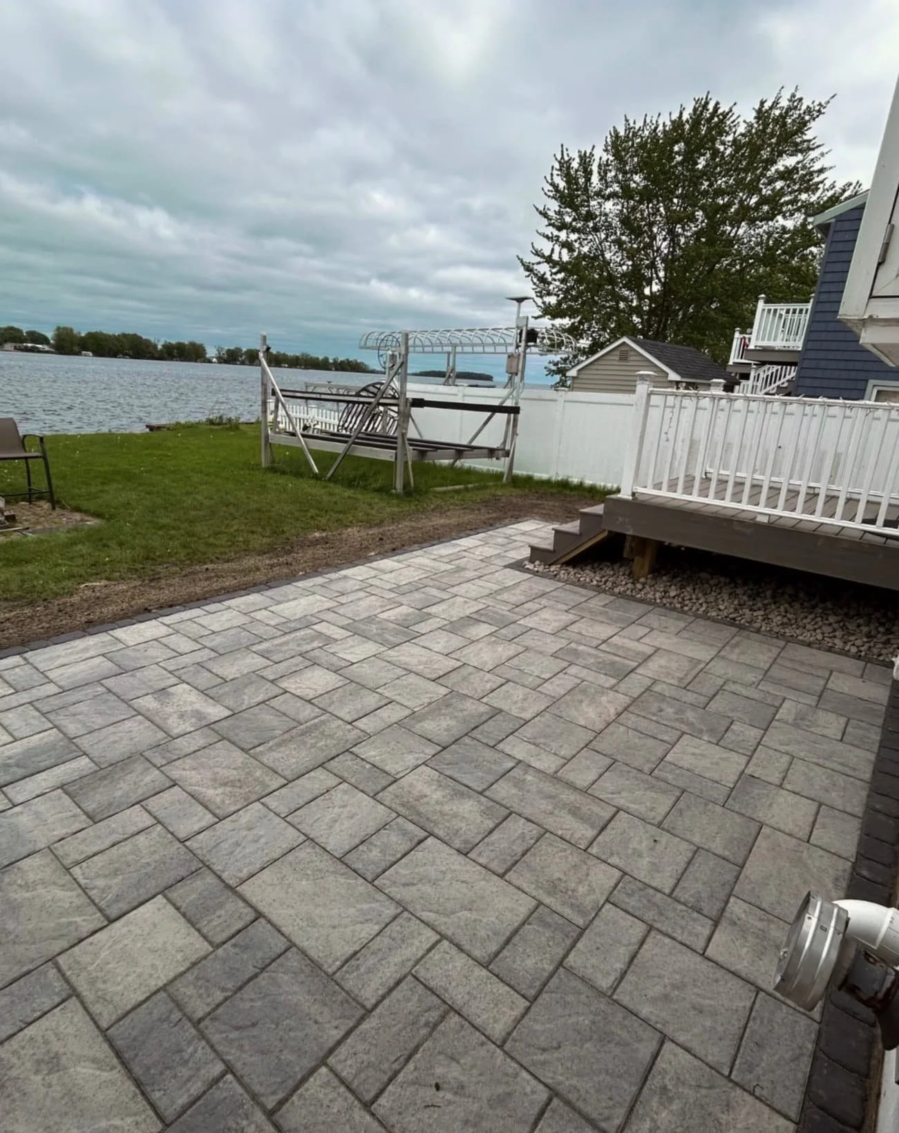 Lakeside paver patio installation in Skaneateles, NY with a spacious hardscape design and waterfront backyard views.