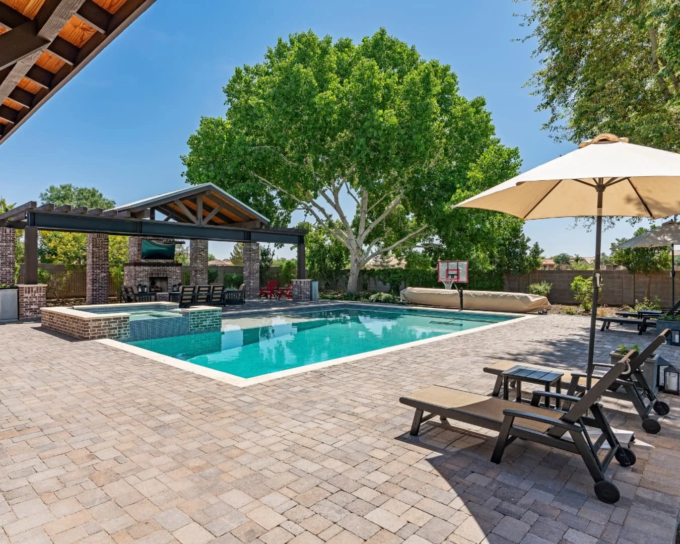 Patio inspiration with a poolside paver layout, lounge chairs, and a spacious backyard setting.