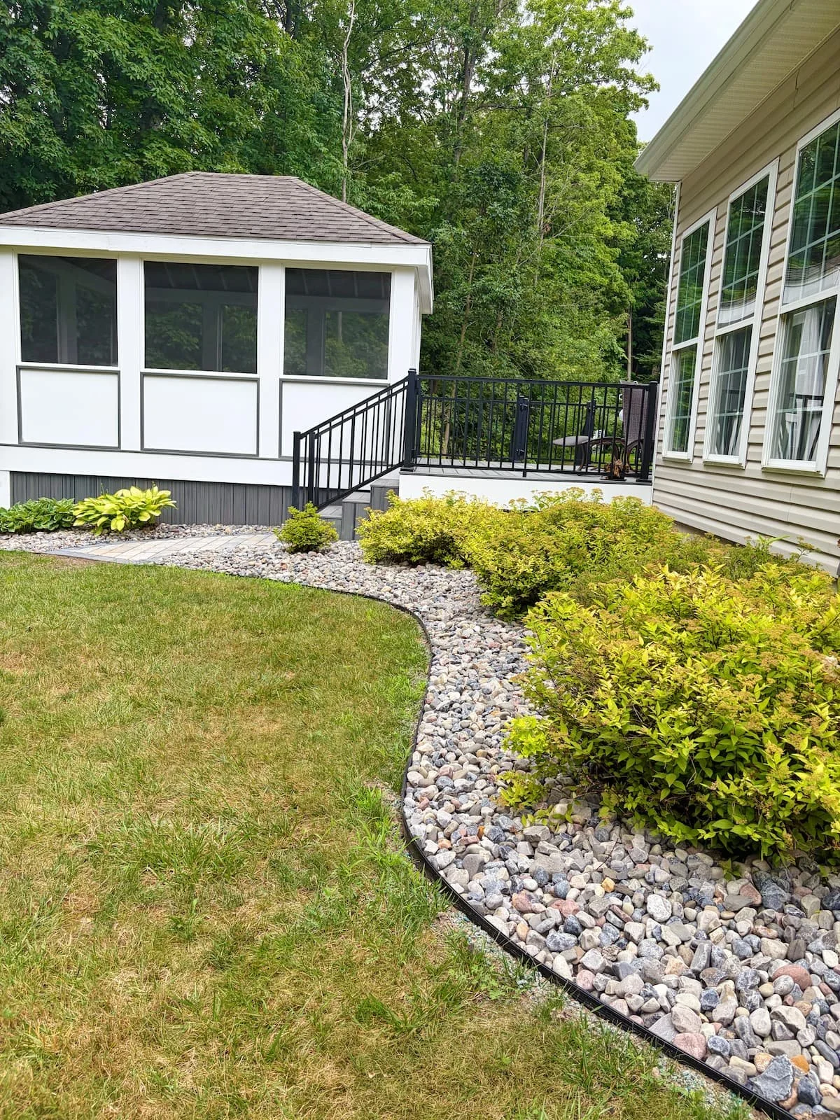 Custom paver walkway bordered by river rock and evergreen landscaping at a Central NY home.
