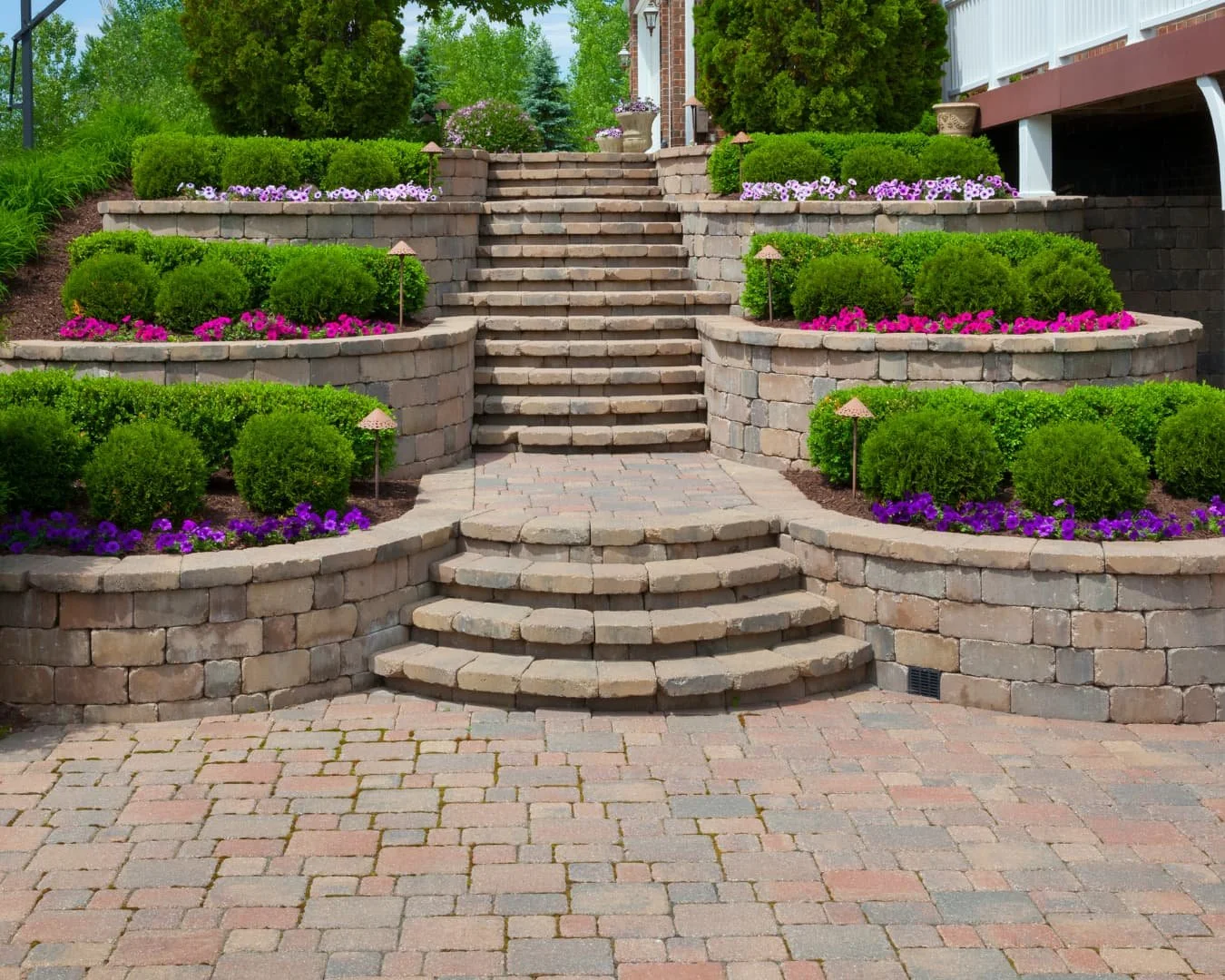 Stair inspiration featuring tiered paver steps with curved lines and structured planting beds on both sides.