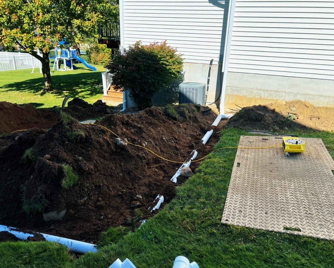 Side yard landscape bed at a Baldwinsville, NY home with fresh mulch, stone edging, and neat plant placement.