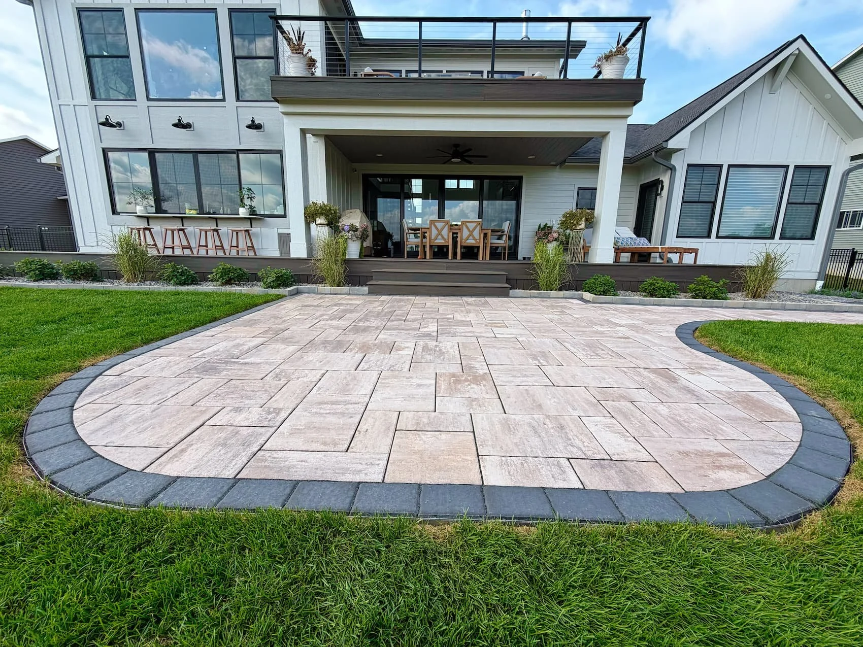 Backyard paver patio framed by lawn and residential landscaping in Central NY