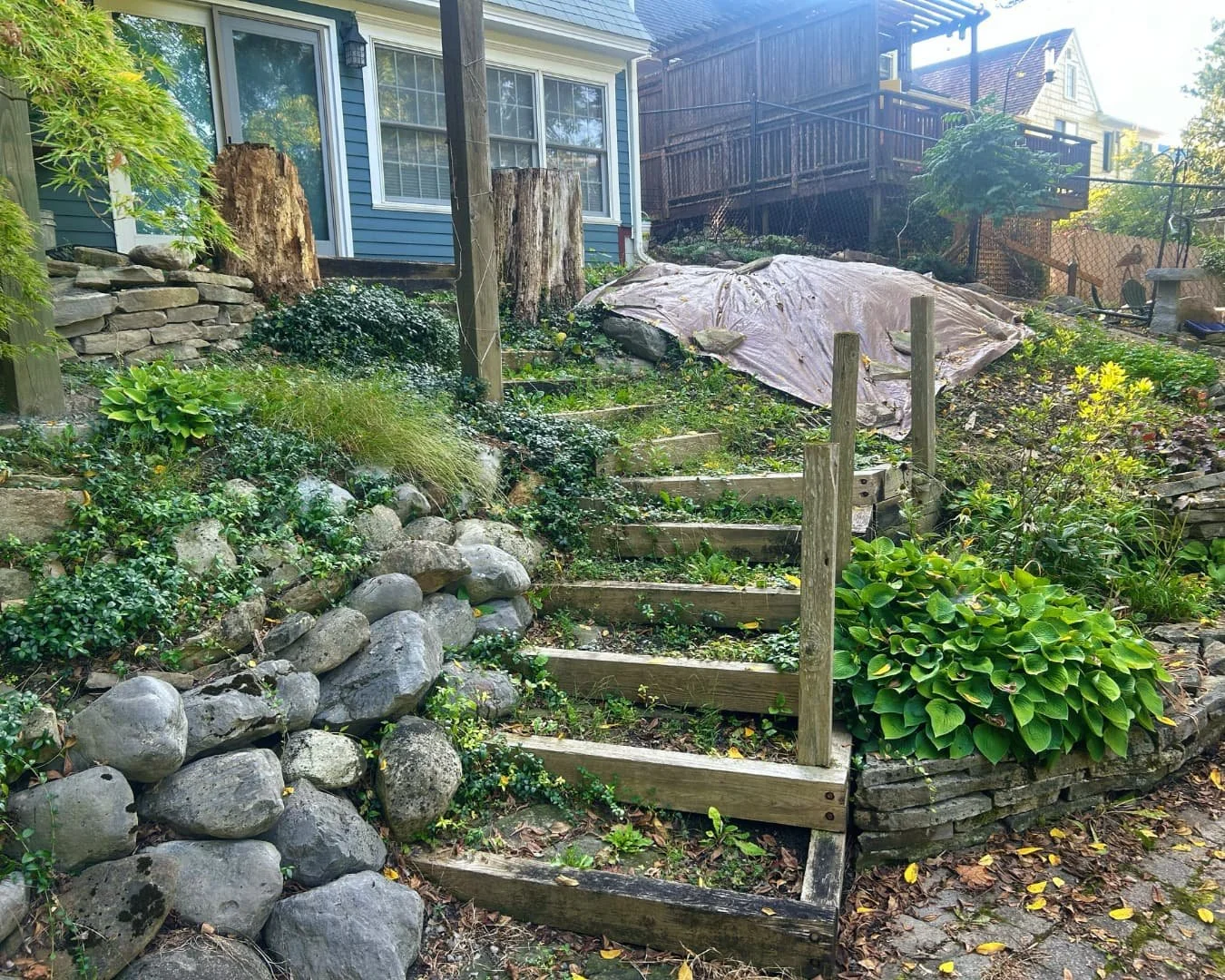Existing backyard steps and retaining area before transformation by Pines and Pavers in Central New York.