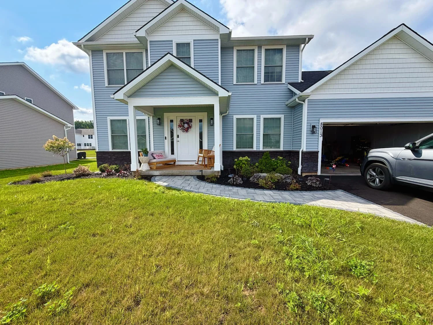 Paver walkway creating a curved path to the home’s front entrance with surrounding landscaping in Central NY.